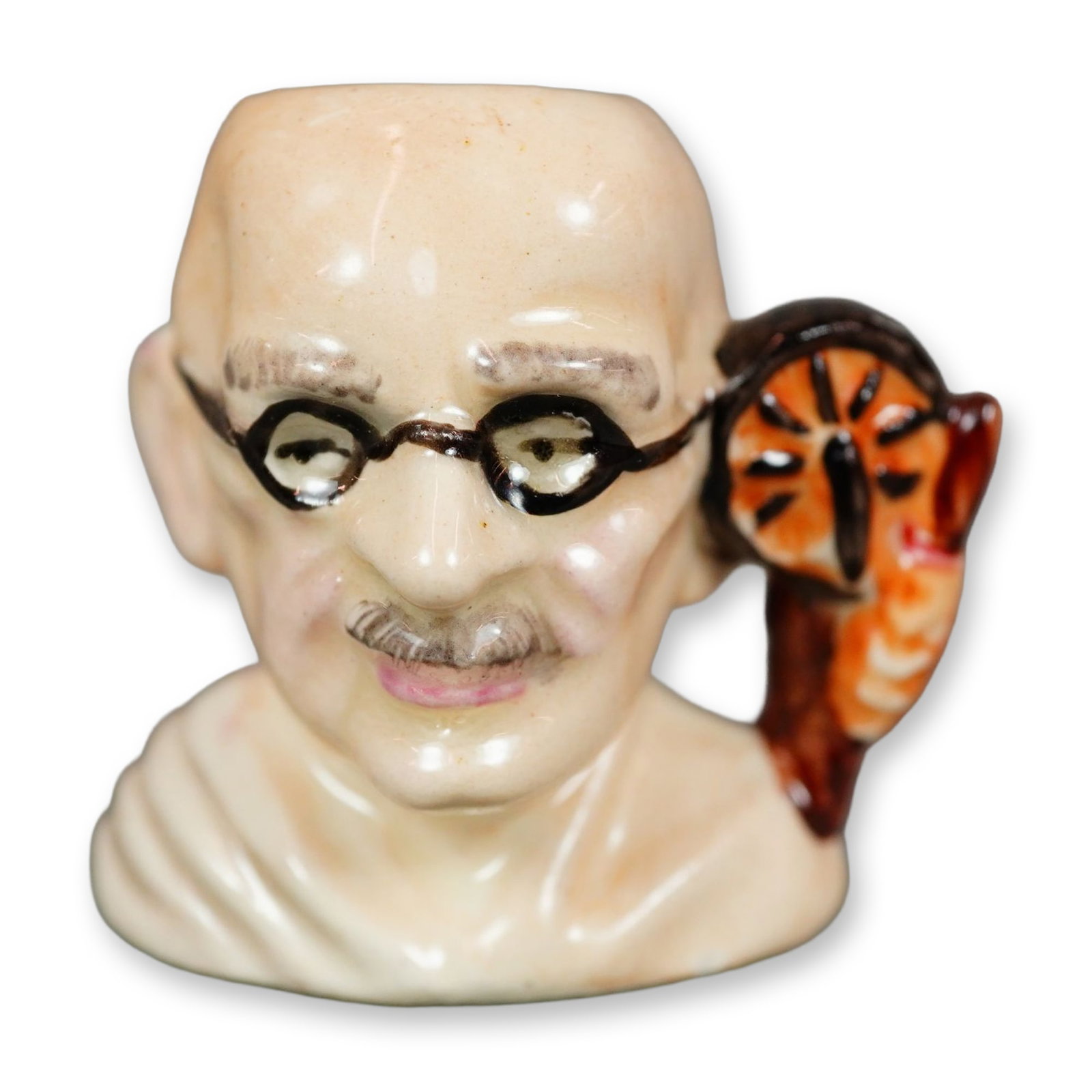 Royal Doulton Prototype Colorway Figurine, Gandhi: Royal Doulton figural character jug modeled after Mahatma Gandhi. Depicts Gandhi wearing a white draped cloth. The handle is formed as a salt cart and a hand holding a walking stick in brown and orang
