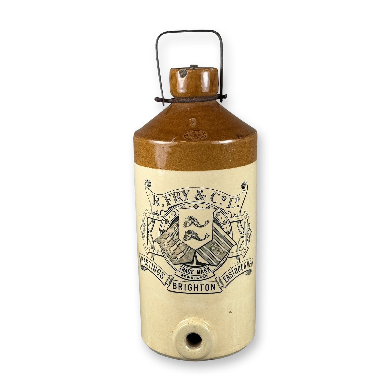 R. Fry & Co Limited, Brighton, Hastings, Eastbourne, Stoneware Flagon with Metal Handle: Depicted in brown and tan with a salt-glazed finish. Features R. Fry & Co Limited logo on the sides. Dimensions: Approximately: 8.5"W x 19"H Weight: 16.54 lbs