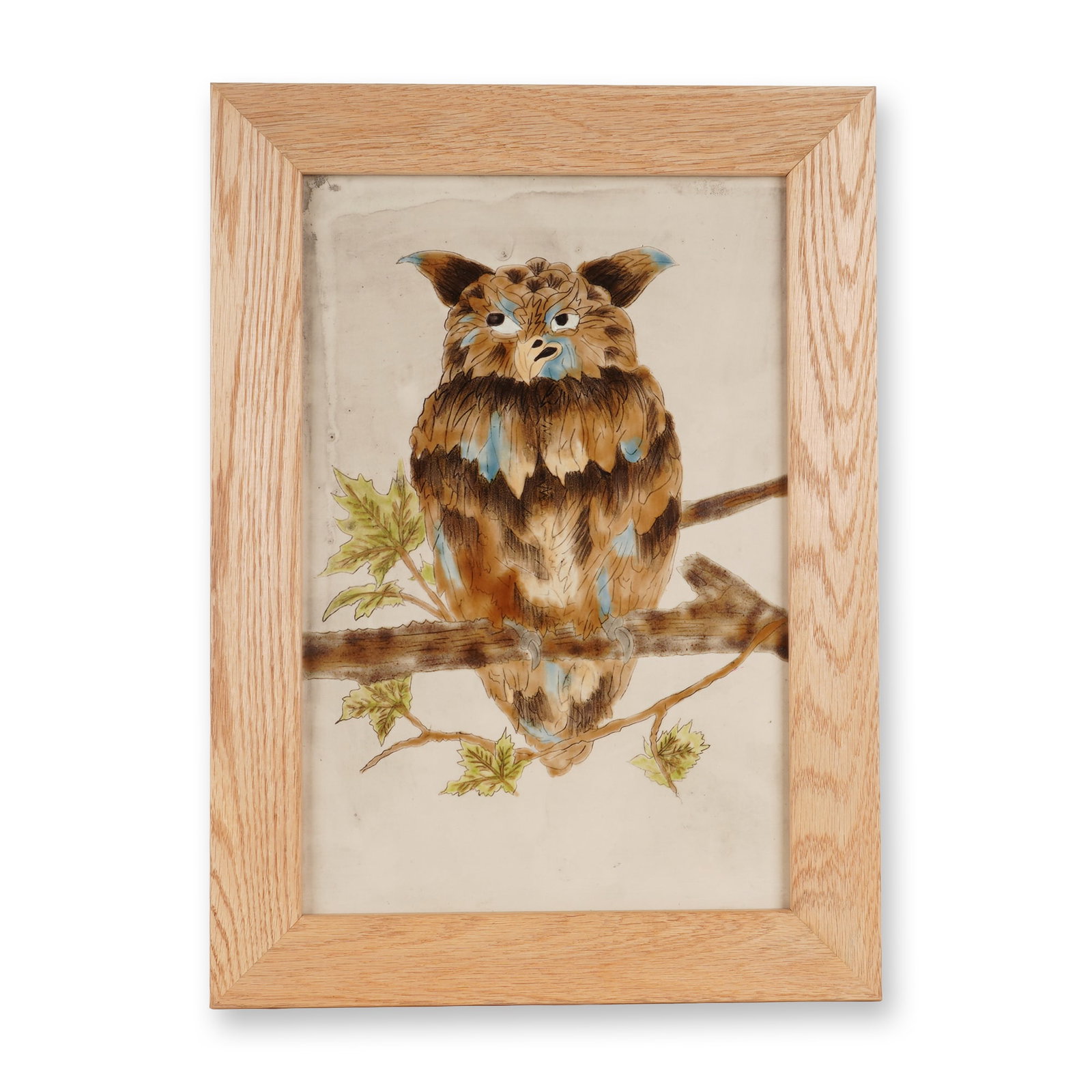 Framed Cobridge Stoneware Grotesque Owl Plaque: A glazed stoneware tile plaque depicting a grotesque owl perched on a branch with leaves. The composition is rendered in shades of brown, blue, and green, on a cream-colored ground with faint gray hue