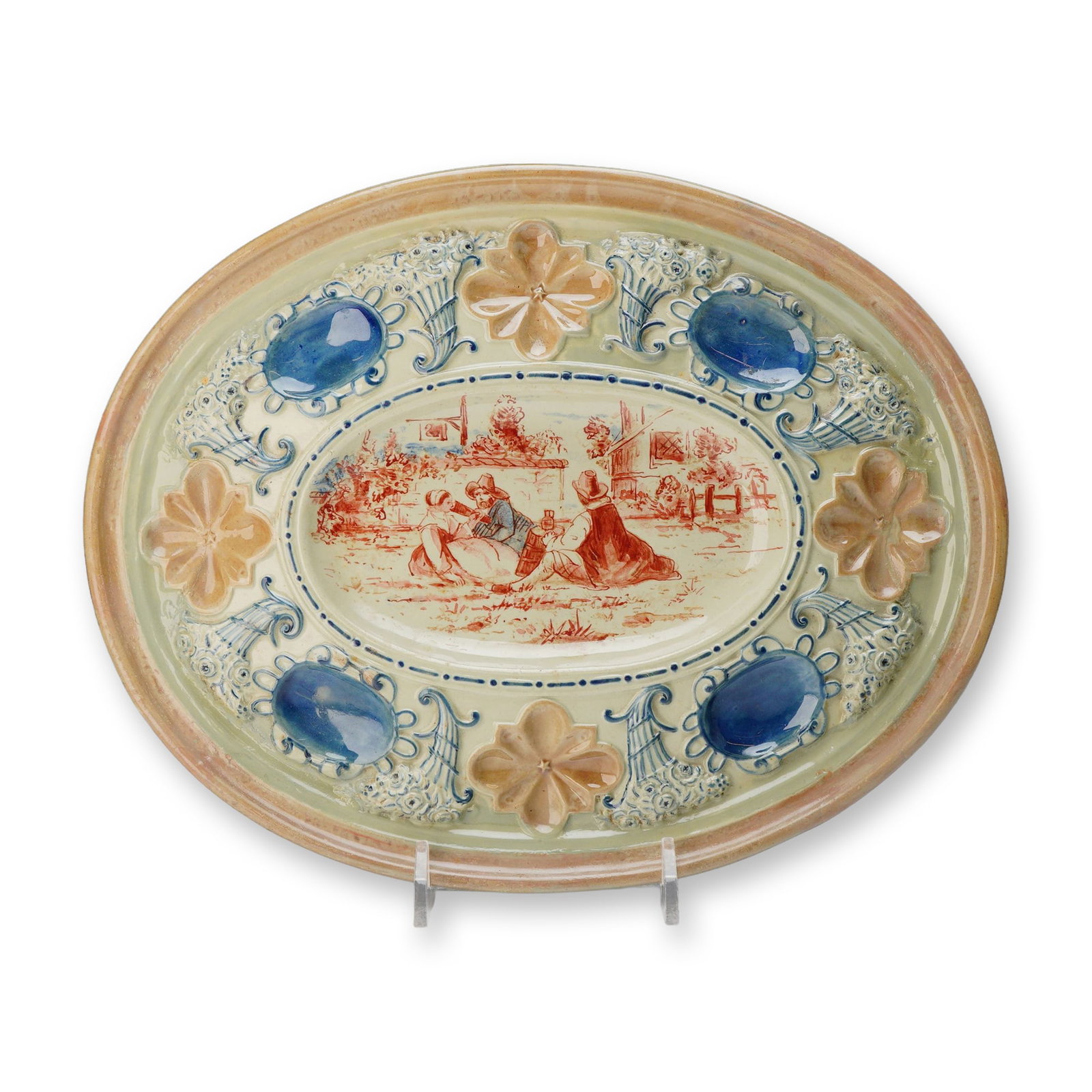 Wedgwood Majolica Oval Platter with Genre Scene: This Wedgwood glazed earthenware oval platter features a central recessed well decorated with a reddish-brown monochrome genre scene. The scene depicts three rustic figures seated outdoors in conversa