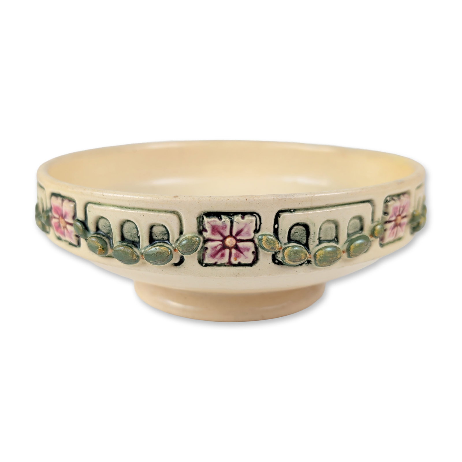 Arts and Crafts Floral Pottery Console Bowl: A earthenware console bowl featuring a molded relief border of stylized four-petal pink flowers, framed by geometric panels and accented with raised green jeweled ovals. A smooth, glossy cream-colored