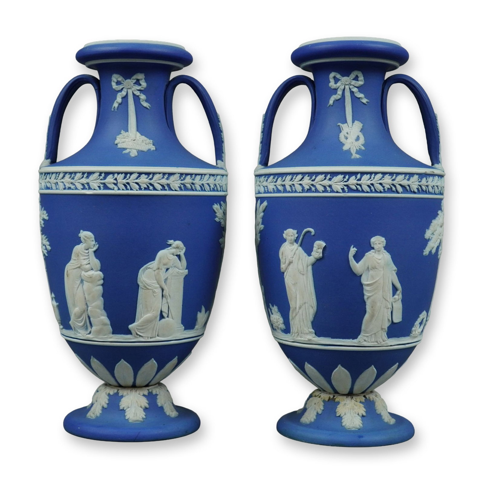 2pc Wedgwood Blue and White Jasperware Vases: A pair of Wedgwood blue and white jasperware vases. These items are designed as twin-handled amphora-shaped urns mounted on separate pedestal bases, held together with central metal rods and nuts visi