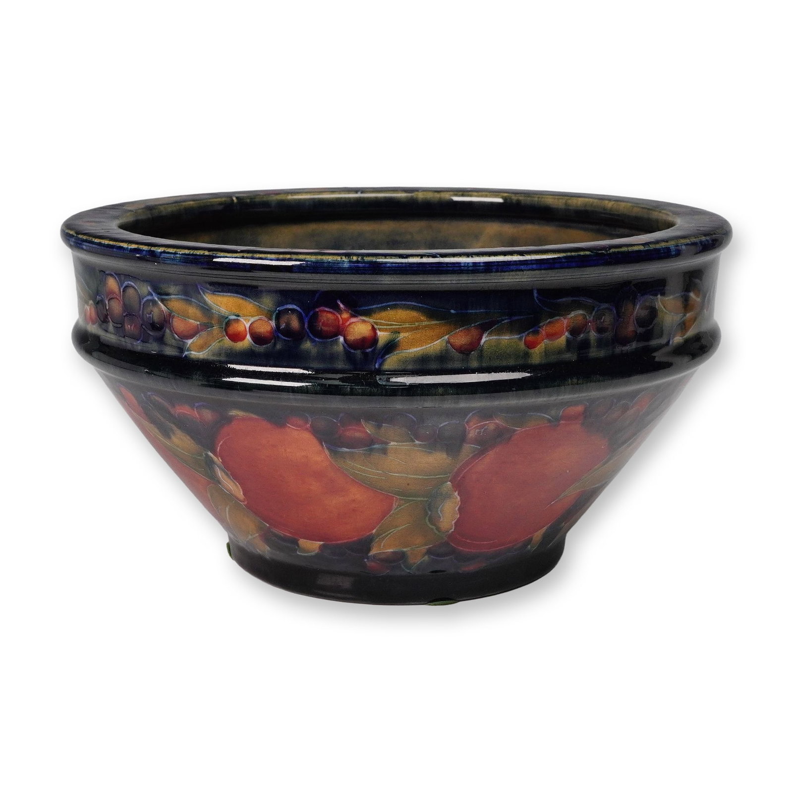 William Moorcroft Pottery Bowl, Pomegranate: An early, pottery circular bowl. It is decorated to the interior and exterior with fruit clusters and scrolling foliage against a rich cobalt-blue ground in the tube lined technique. Signed "W Moorcro