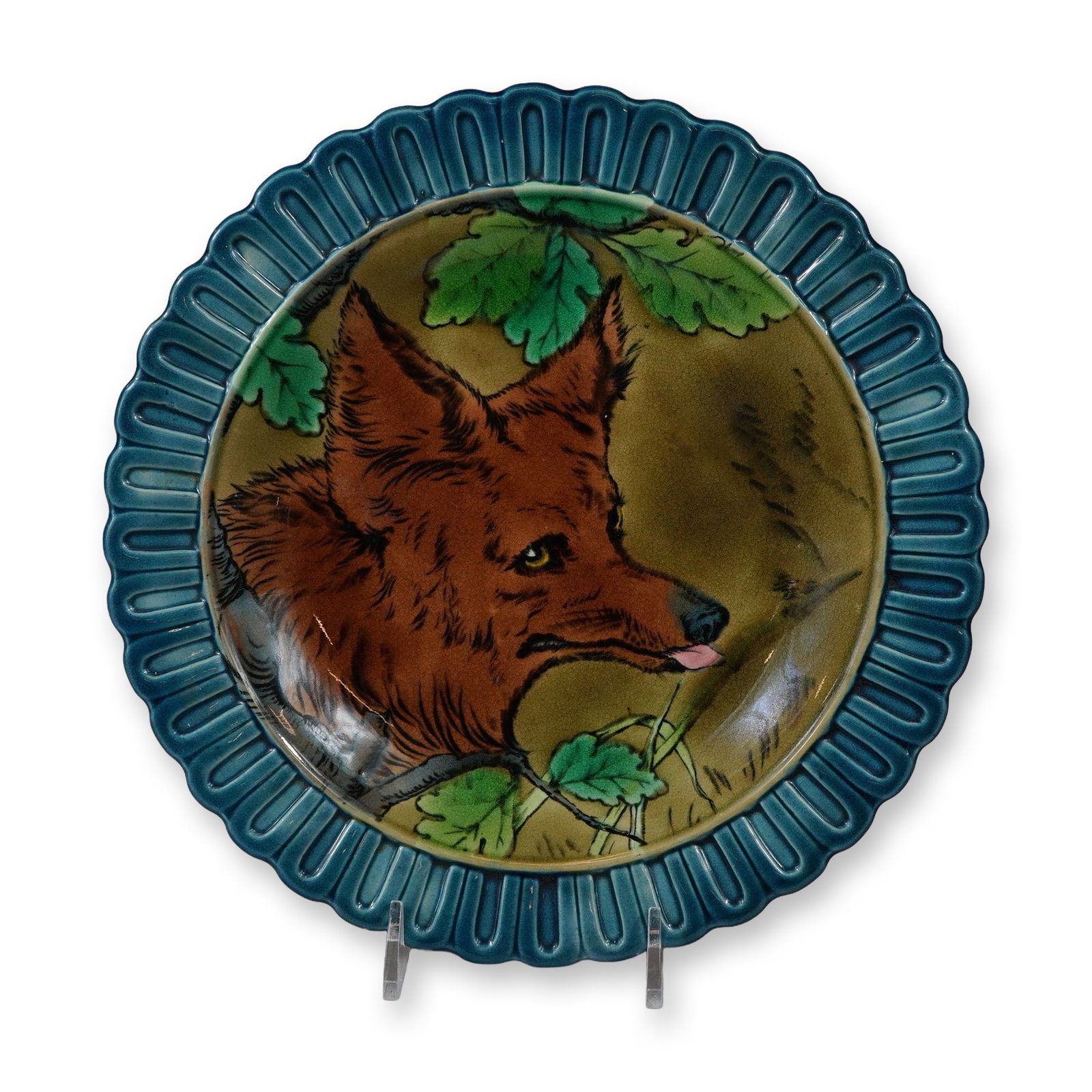 Rare Wedgwood Majolica Fox Plate: This circular majolica glazed earthenware plate was manufactured by Wedgwood in England. The central well features a molded relief decoration of a fox head in profile facing right with its tongue slig