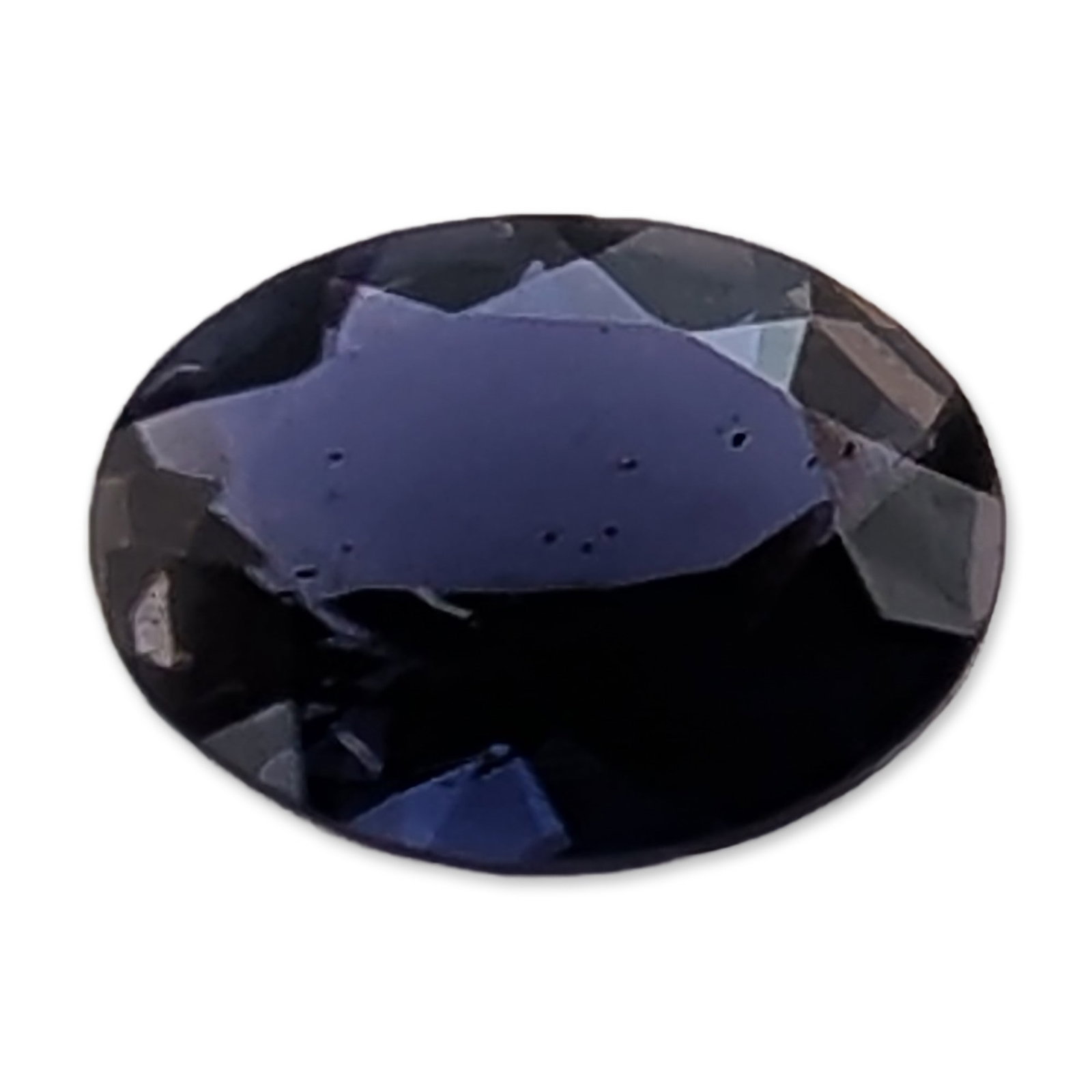 Loose Oval Cut Blue Tourmaline Gemstone: Faceted Tourmaline gemstone. Loose oval cut stone in dark navy to indigo blue, featuring a deep pavilion and faceted crown. Color shows subtle violet undertones under direct light. Significant girdle 