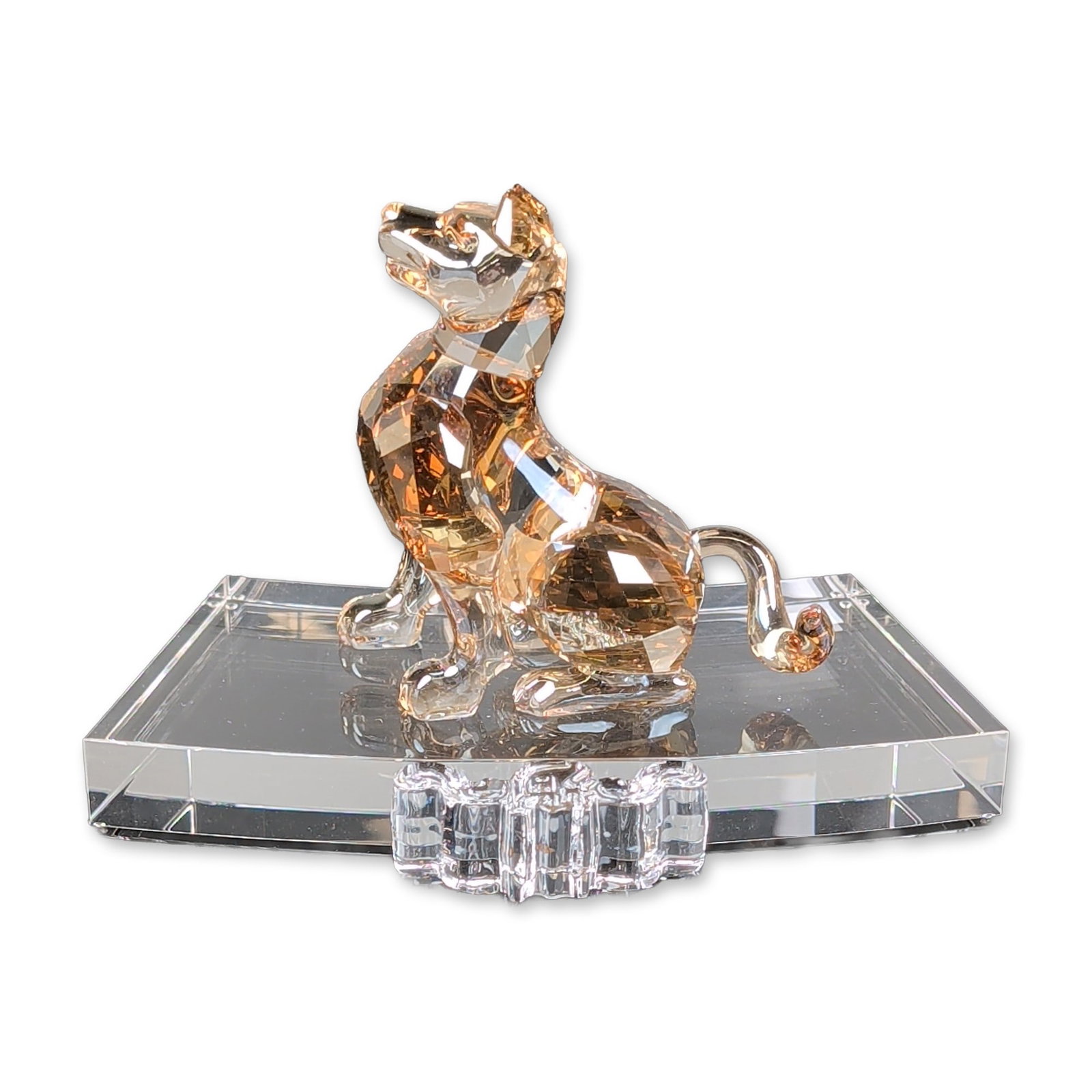 Swarovski Crystal Figurine, Chinese Zodiac Gold Dog: This piece is crafted from multi-faceted lead crystal, featuring a dog in Golden Shadow amber-toned crystal in a sitting attention pose on a curved clear crystal rectangular slab. The design includes 