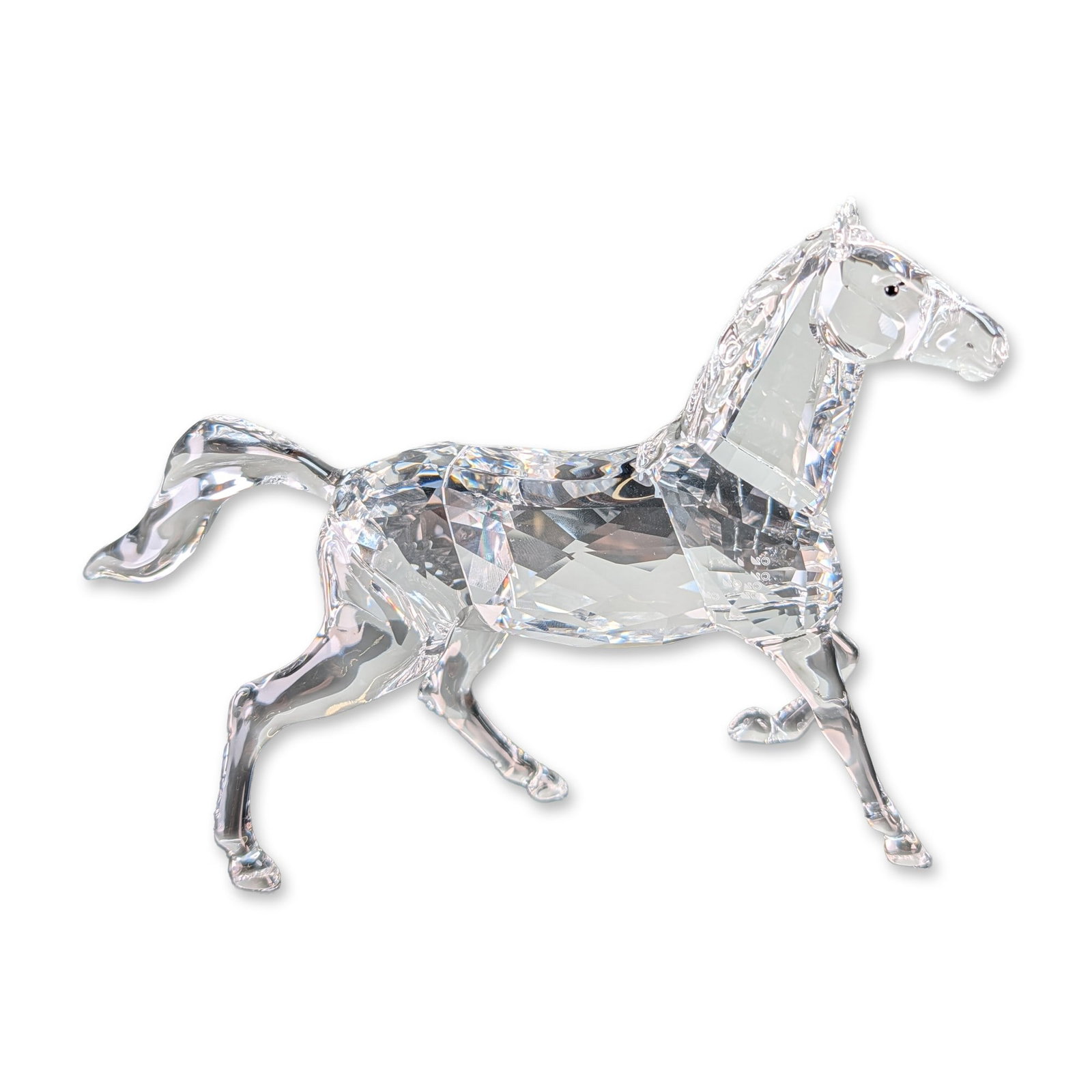 Swarovski Crystal Running Stallion Figurine: Swarovski crystal Stallion figurine depicting a horse in a galloping pose. The piece is constructed from clear faceted lead crystal with a multi-faceted torso and smooth, flowing mane and tail. The he
