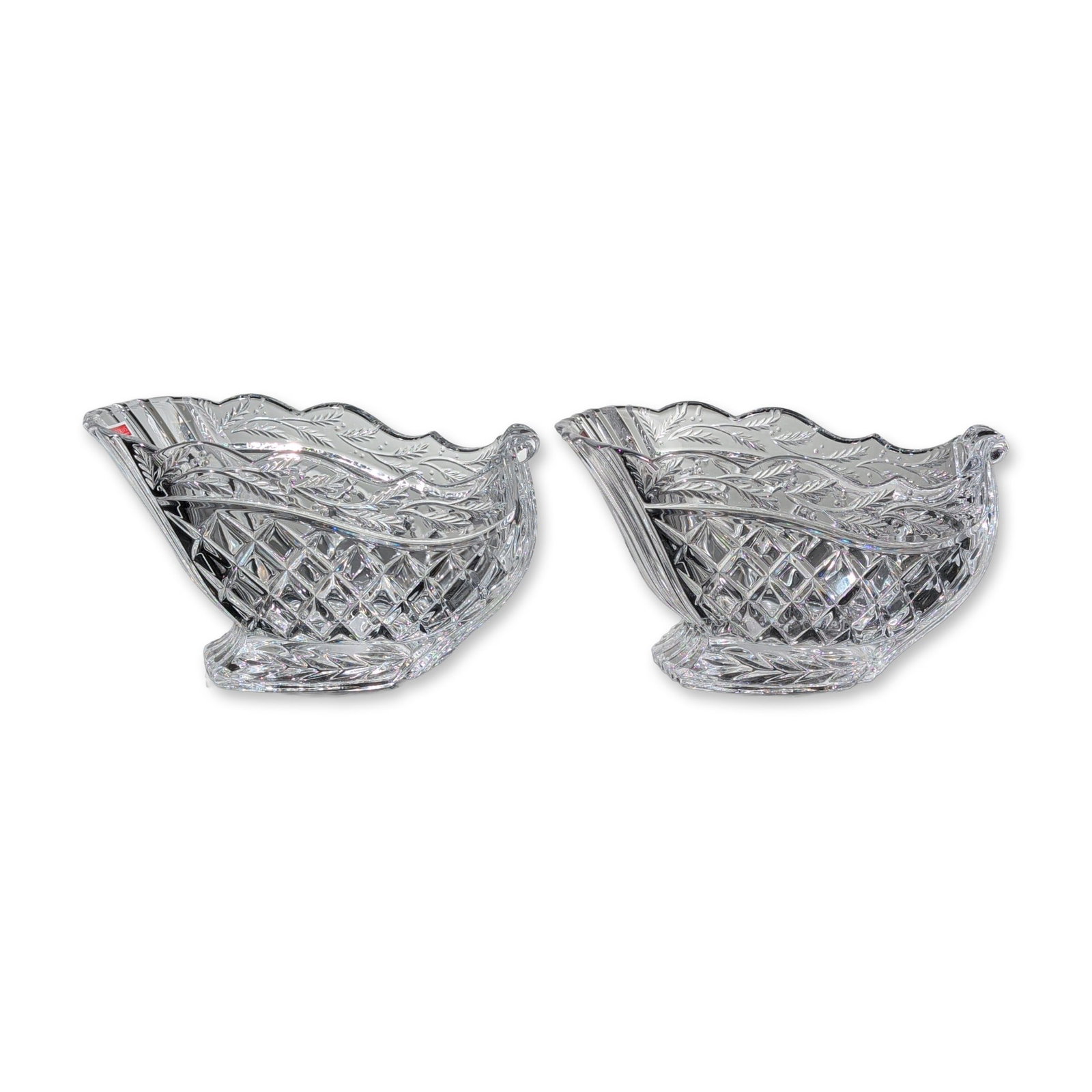 Pair of Marquis by Waterford Crystal Holiday Sleighs: Pair of sleigh-form holiday bowls in lead crystal, produced in Germany. Each piece features a scalloped rim above a body decorated with deep-cut diamond patterns and etched scrolling leaf and berry mo