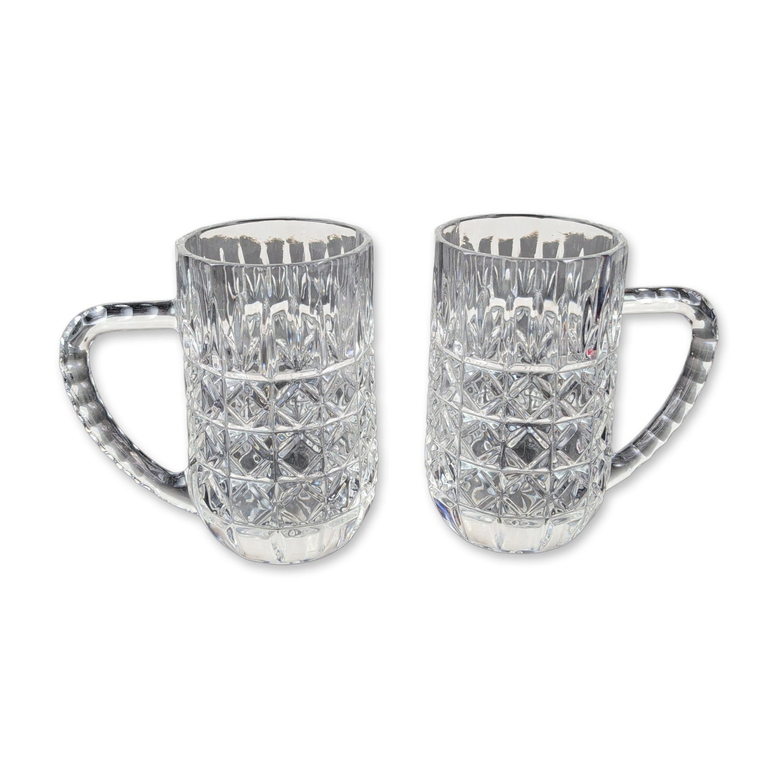 Pair of Crystal Tankards, Attributed to Anchor Hocking: Pair of crystal tankards in lead glass, featuring a lower band of diamond-cut crosshatching beneath vertical wedge flutes. Each vessel is fitted with a substantial C-scroll handle with horizontal notc