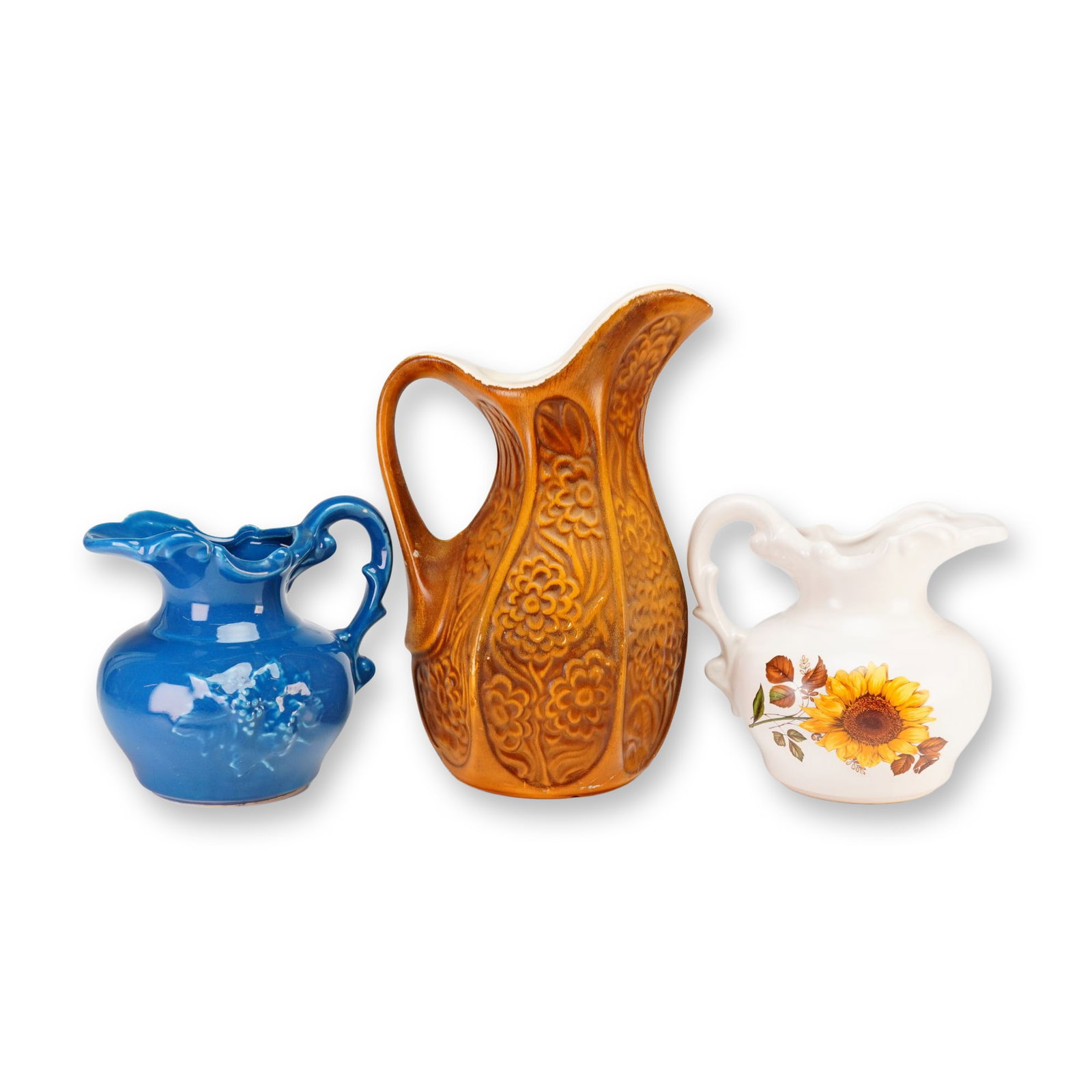 3pc McCoy and Unmarked Ceramic Pitchers: A collection of three glazed ceramic pitchers including a McCoy Pottery Chrysanthemum pattern pitcher and two unmarked examples. The McCoy pitcher features an amber glaze on a hexagonal body with a re