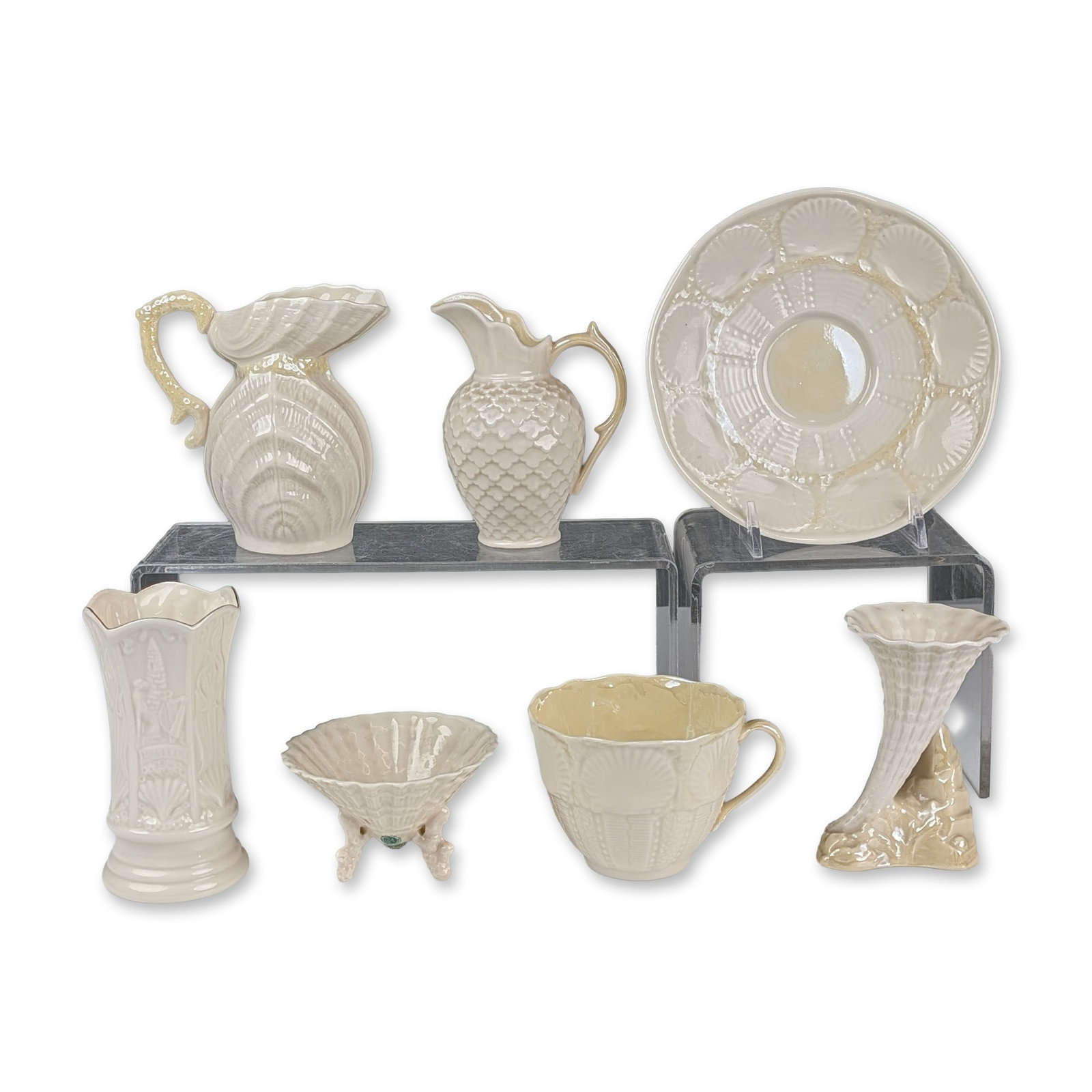 7pc Collection of Belleek Ireland Parian Porcelain Vases, Creamers, Cup and Saucer Set: Belleek Pottery collection of Irish Parian porcelain items featuring an iridescent mother-of-pearl glaze. The assortment includes a nautilus-form pitcher, a scale-textured cream jug, an embossed shell