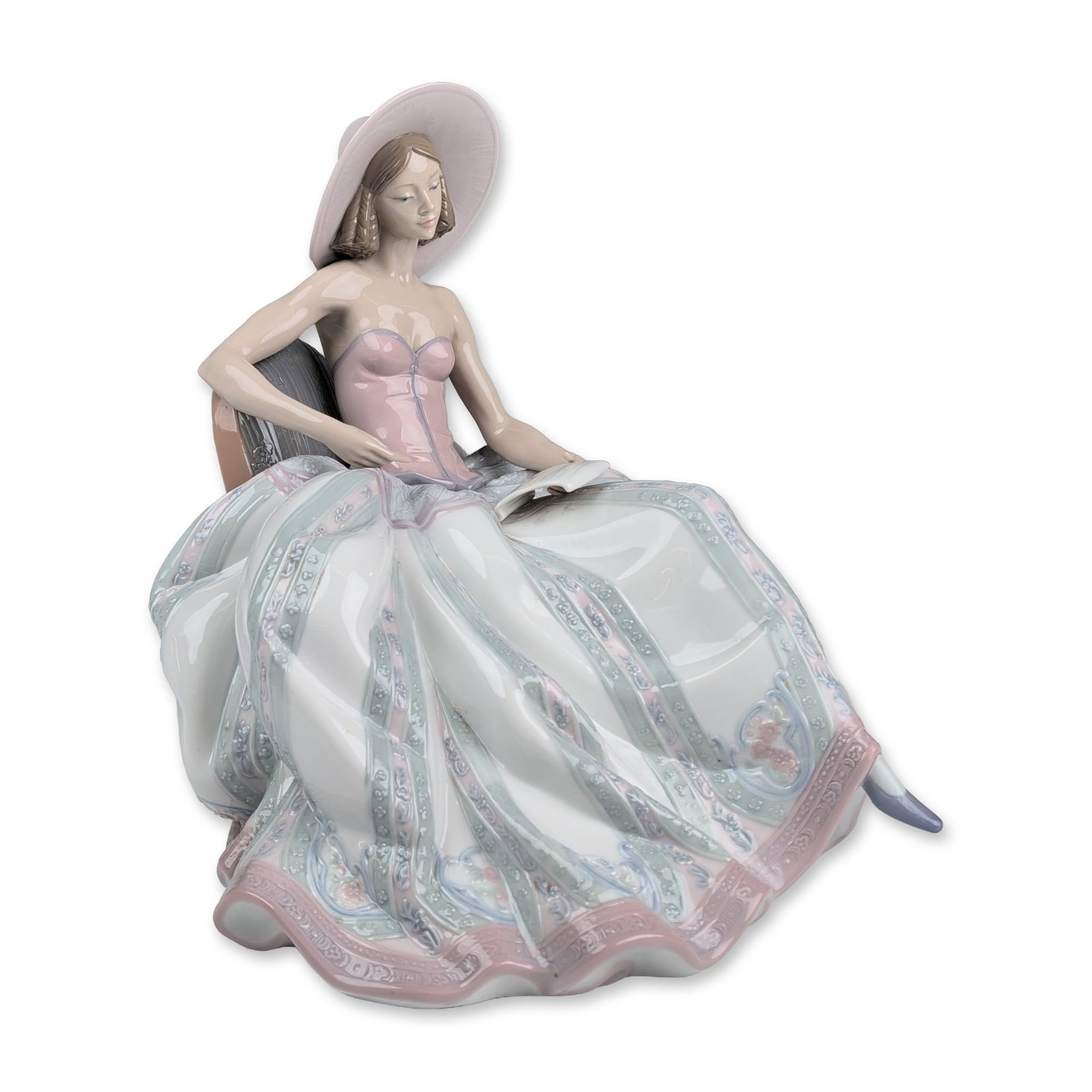 Lladro Porcelain Figurine, Dreaming Of You 01006315: Lladro glazed porcelain figurine titled Dreaming of You, depicting a seated young woman in an elaborate tiered pink and pale green dress with a wide-brimmed hat. The skirt features vertical bands acce