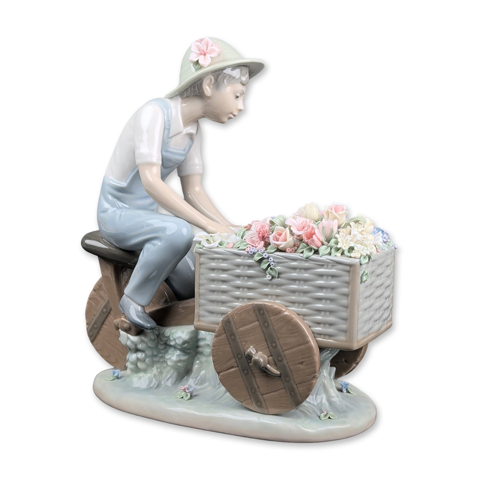 Lladro Porcelain Figurine, Flower Peddler 01005029: Figurine designed by Francisco Catala features a young gardener leaning over a two-wheeled cart filled with hand-applied porcelain flowers. The boy wears a pale green sunhat with a pink flower accent,