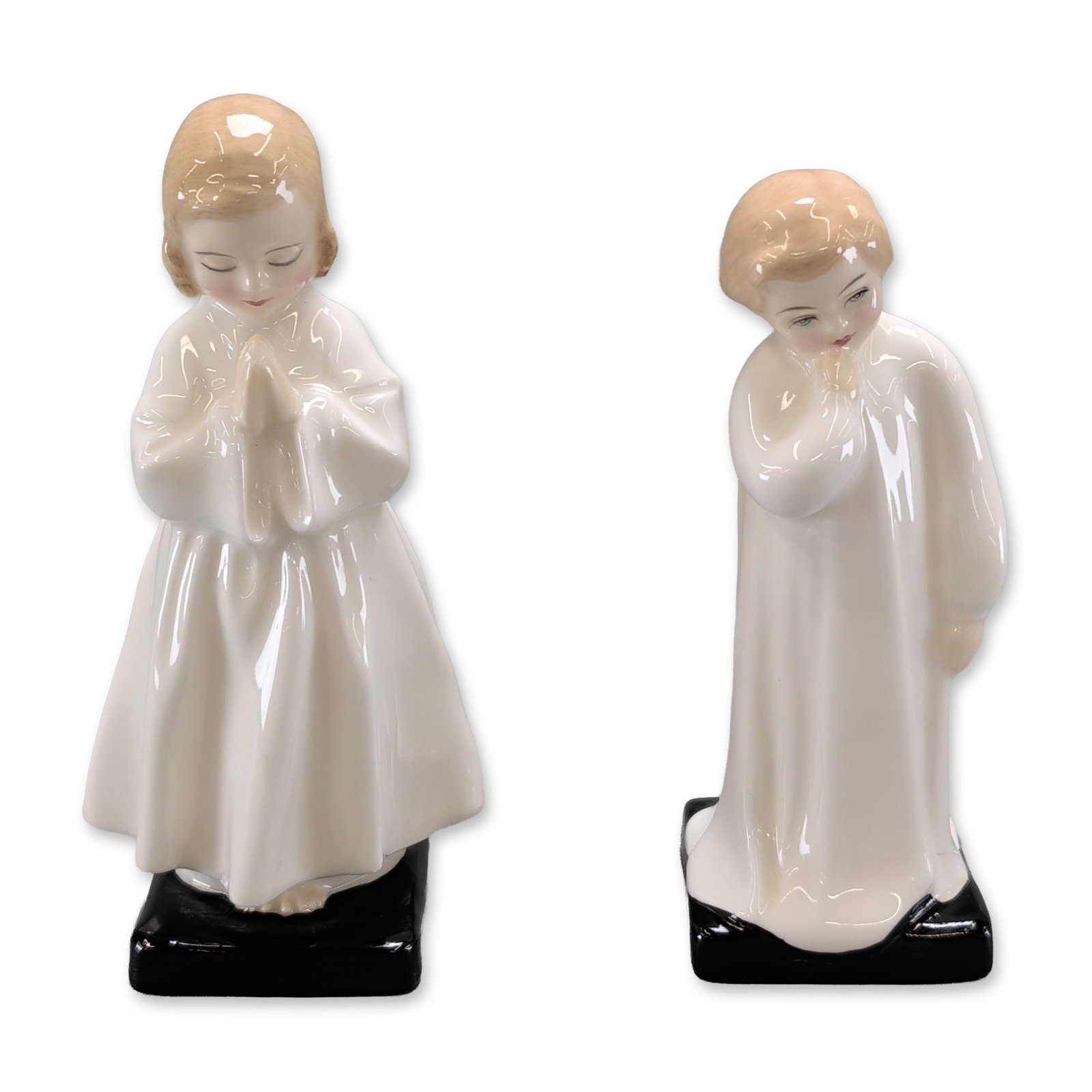 2pc Royal Doulton Figurines, Darling and Bedtime: Royal Doulton. A pair of English bone china figurines, Bedtime and Darling, each modeled as a child in a white nightgown standing on a rectangular black base. Both figures feature a high gloss finish,