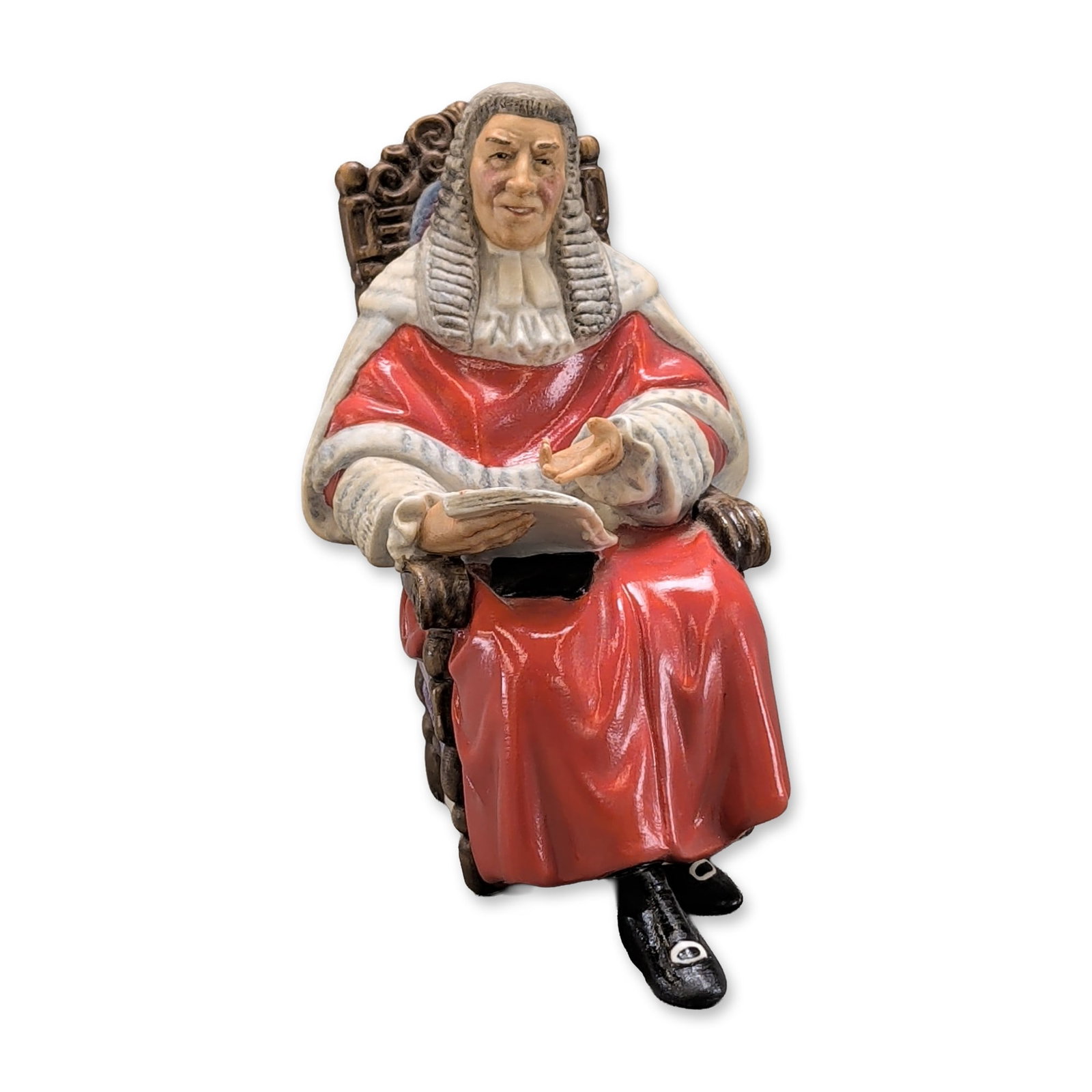 Royal Doulto Porcelain Figurine The Judge: Royal Doulton English porcelain figurine titled The Judge, model HN 2443. The seated figure is depicted in traditional British judicial attire, including scarlet robes with white fur-style trim, a ful