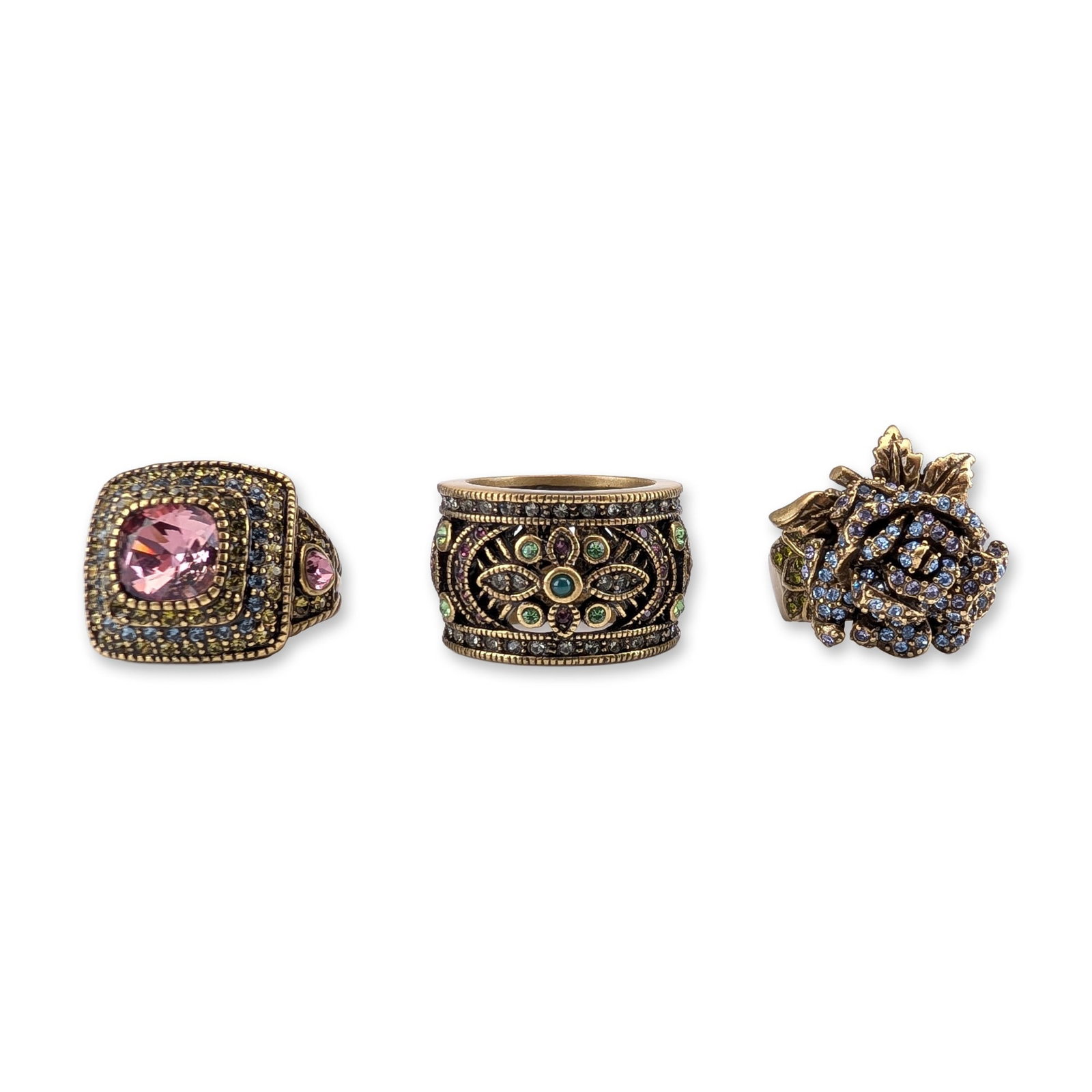 3pc Heidi Daus Crystal Cocktail Rings: Heidi Daus collection of three cocktail rings in antiqued bronze-tone base metal featuring multicolored crystal embellishments. The group includes one ring with a large faceted cushion-cut pink crysta