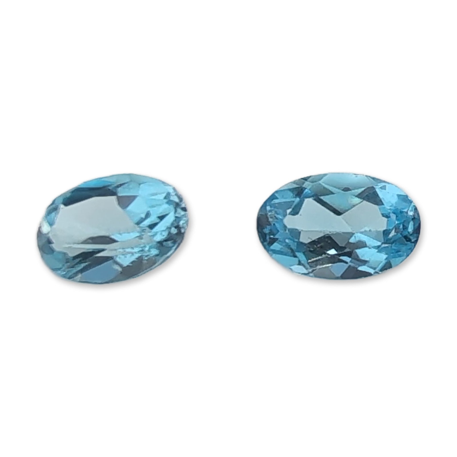 Pair of Oval Light Blue Topaz Gemstones: Pair of matching faceted Topaz gemstones in a uniform light blue color. Each stone is oval cut with high clarity and an eye-clean appearance.Approximate length: 5.9 mmTotal weight: 1.0 ct. Dimensions: