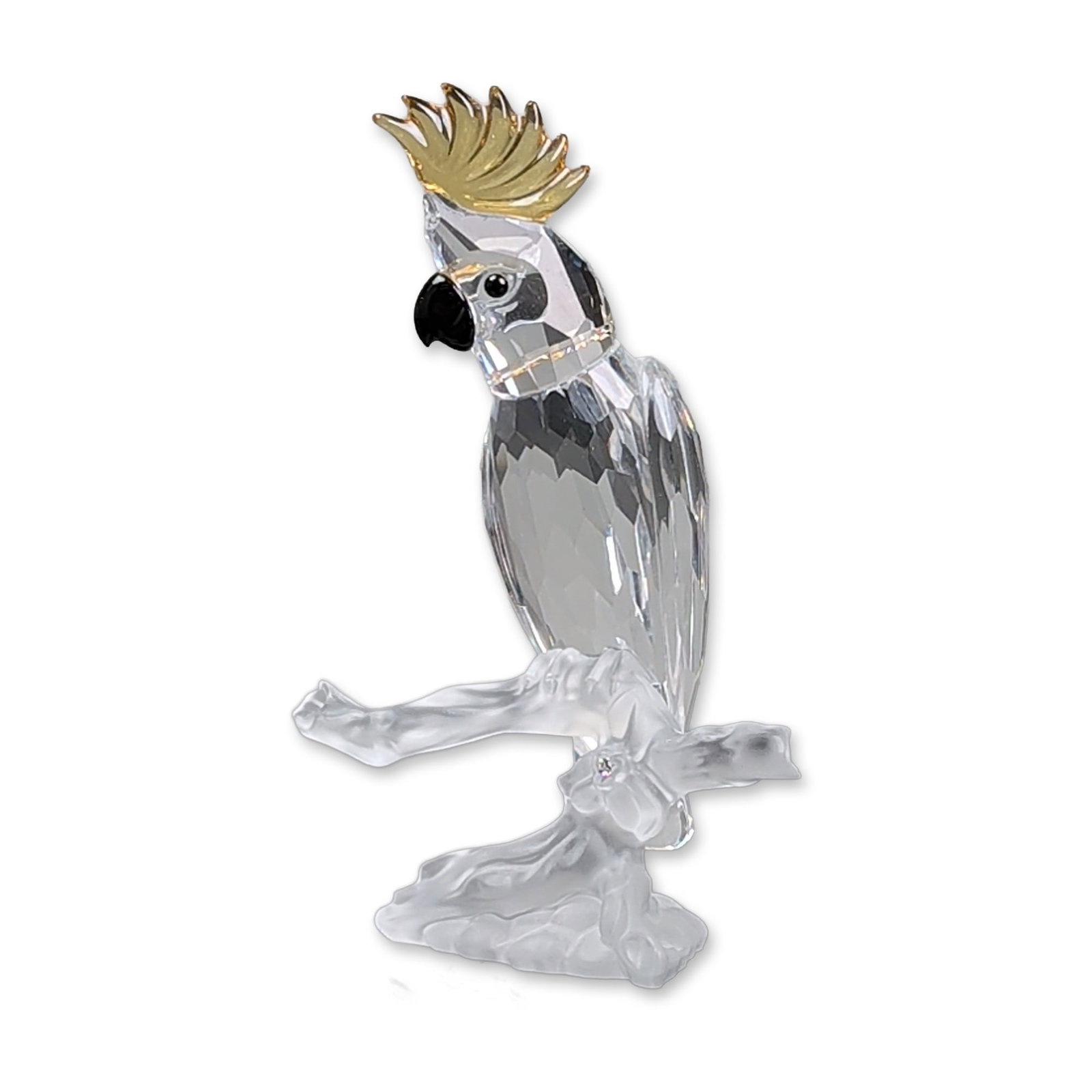 Swarovski Silver Crystal Figurine, Cockatoo: Figurine designed by Heinz Tabertshofer, composed of faceted clear lead crystal with a yellow crystal crest and black crystal eyes and beak. The bird is mounted to a frosted crystal branch base. A las