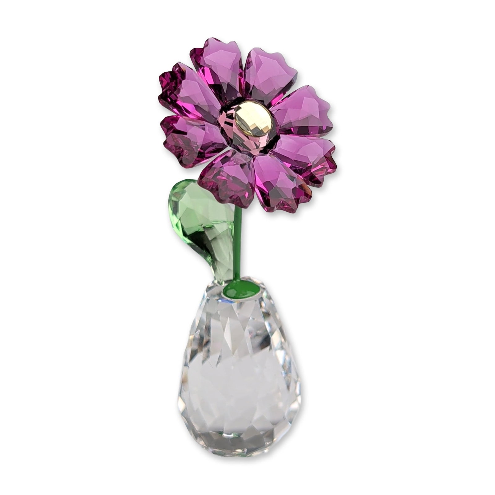 Swarovski Flower Dreams Crystal Figurine, Gerbera: Flower Dreams Gerbera figurine in faceted lead crystal, featuring purple petals, a clear center, a green-coated metal stem with a faceted green leaf, and a clear bulbous faceted vase. Swan logo with c