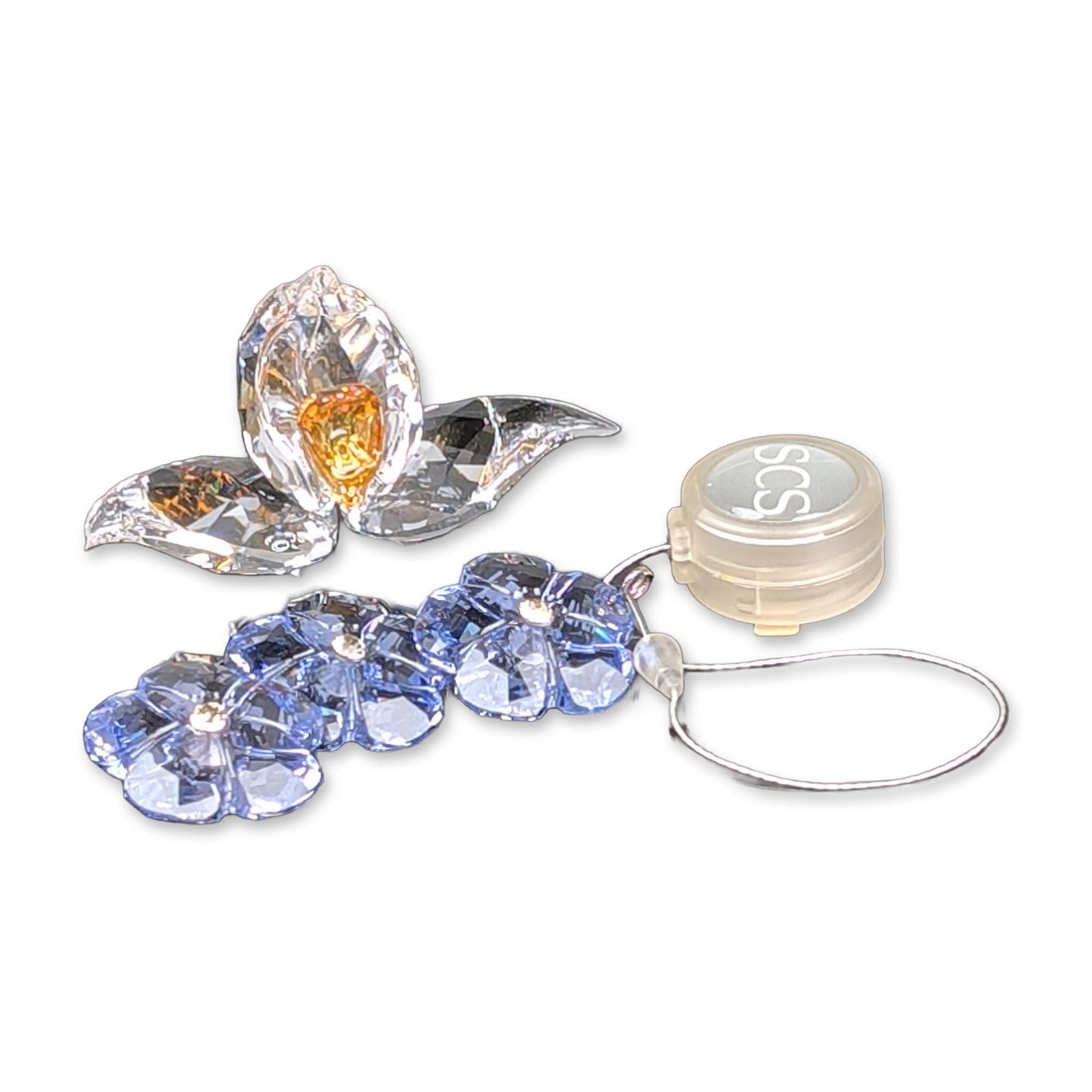 Two Swarovski SCS Crystal African Orchid Figurine and Blue Flower Ornament: The clear crystal orchid with an amber-toned center is paired with a vertical spray of three blue flowers in sapphire and periwinkle toned window ornament. One orchid petal bears an etched Swarovski s