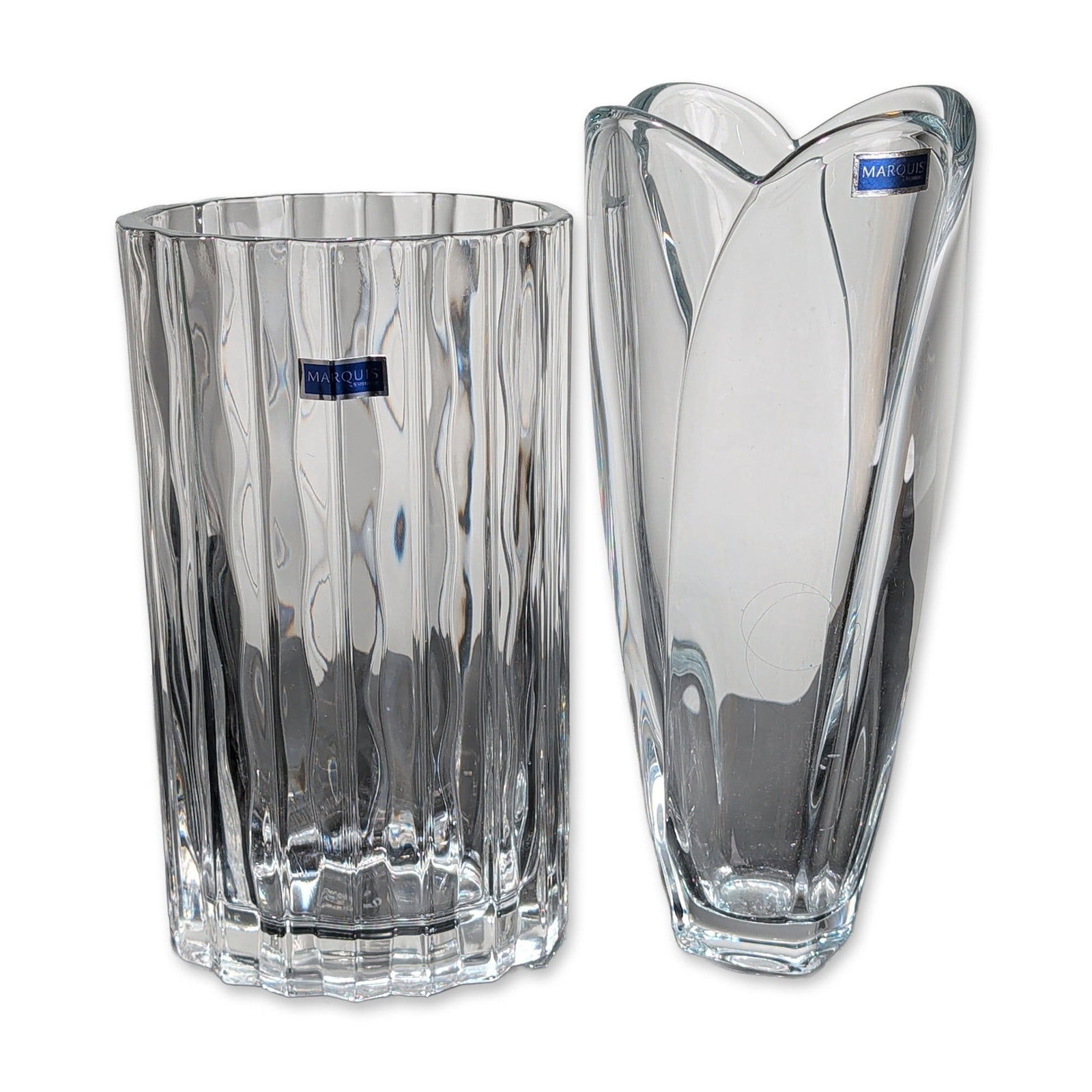 Two Marquis by Waterford Crystal Vases: Marquis by Waterford clear crystalline vases in two contemporary designs. One vase features a flared rim with three overlapping petal forms tapering to a weighted square base. The second vase is a str