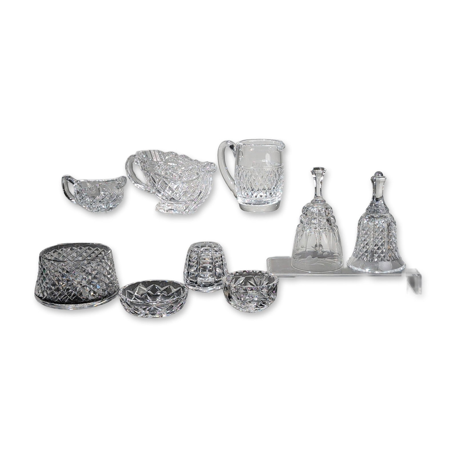 Collection of Nine Waterford and Cut Crystal Pieces including Hand Bells: Collection of nine pieces in various hand-cut patterns featuring signature diamond and wedge cuts. The grouping includes one pitcher with a star-cut base and polished handle, one serving bowl, one cre