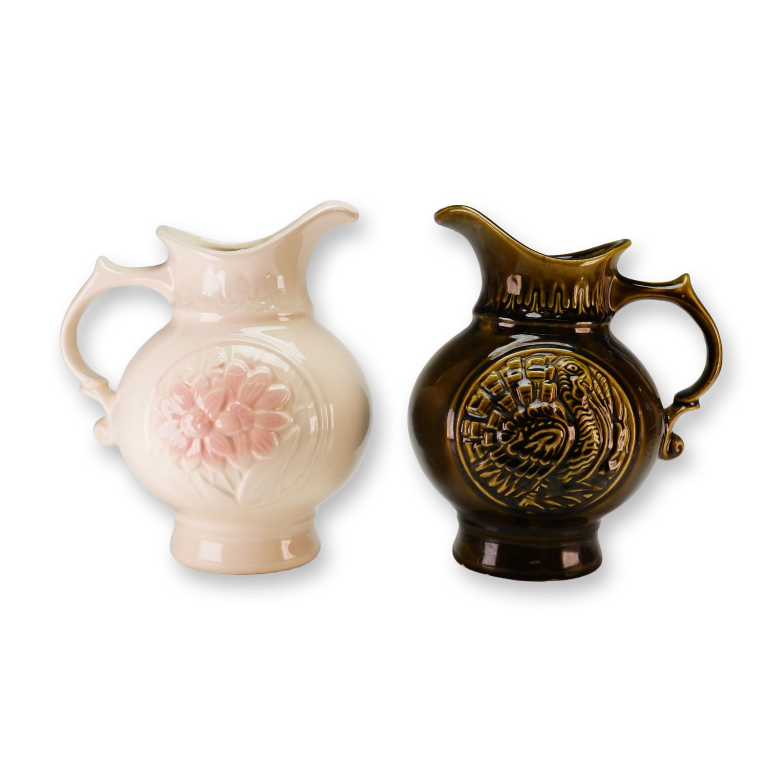 Two McCoy MCP Glazed Pottery Pitchers: This lot features 2pc McCoy and MCP pottery pitchers dating to 1968. Each glazed ceramic vessel is constructed with a globular body, a flared rim with an integrated spout, and a decorative scrolled ha