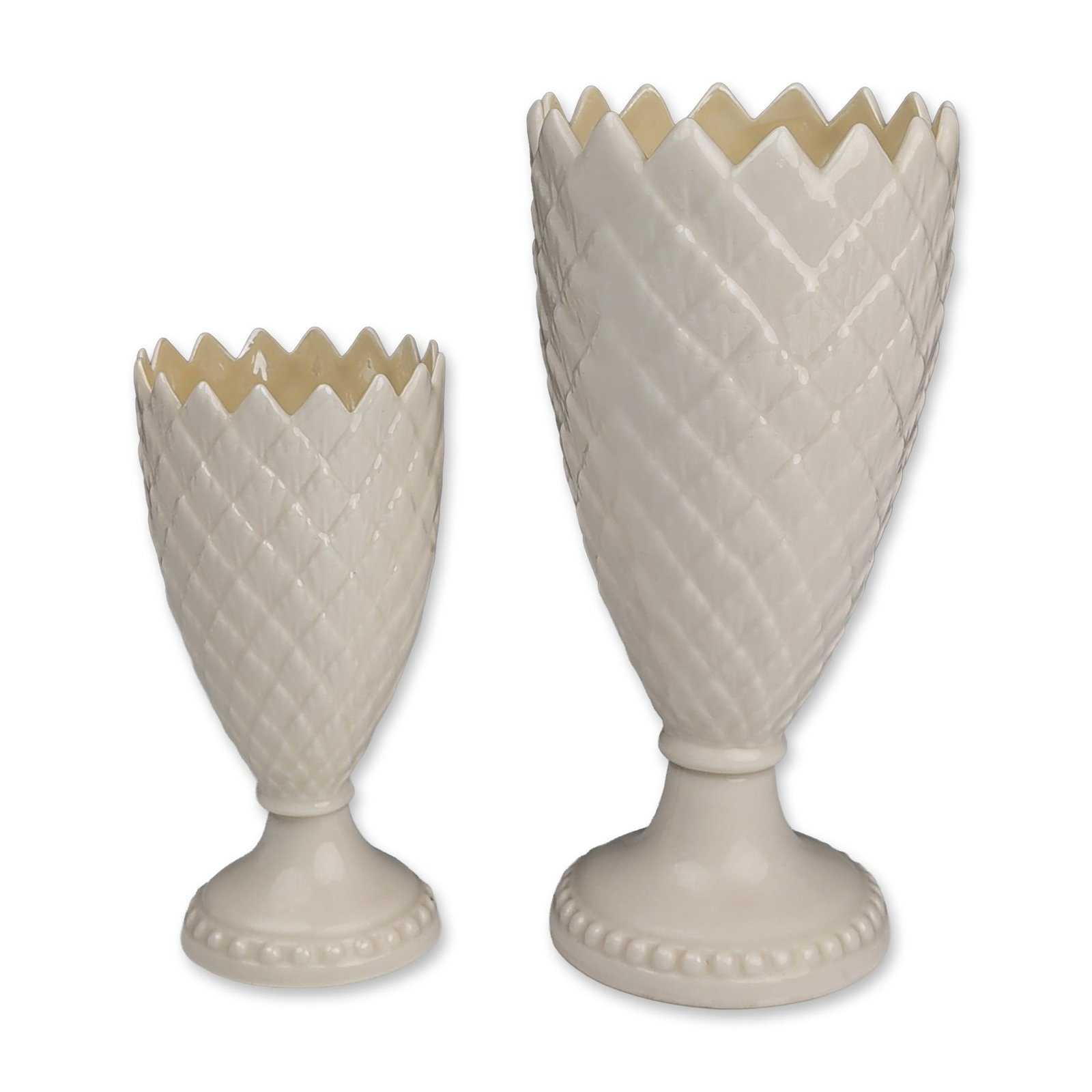 Two Belleek Ireland Porcelain Thistle Vases: Belleek Pottery, Ireland. Graduated pair of vases in cream parian porcelain, featuring the Thistle pattern with a molded diamond lattice body and serrated upper rim. Each vase rests on a footed circul