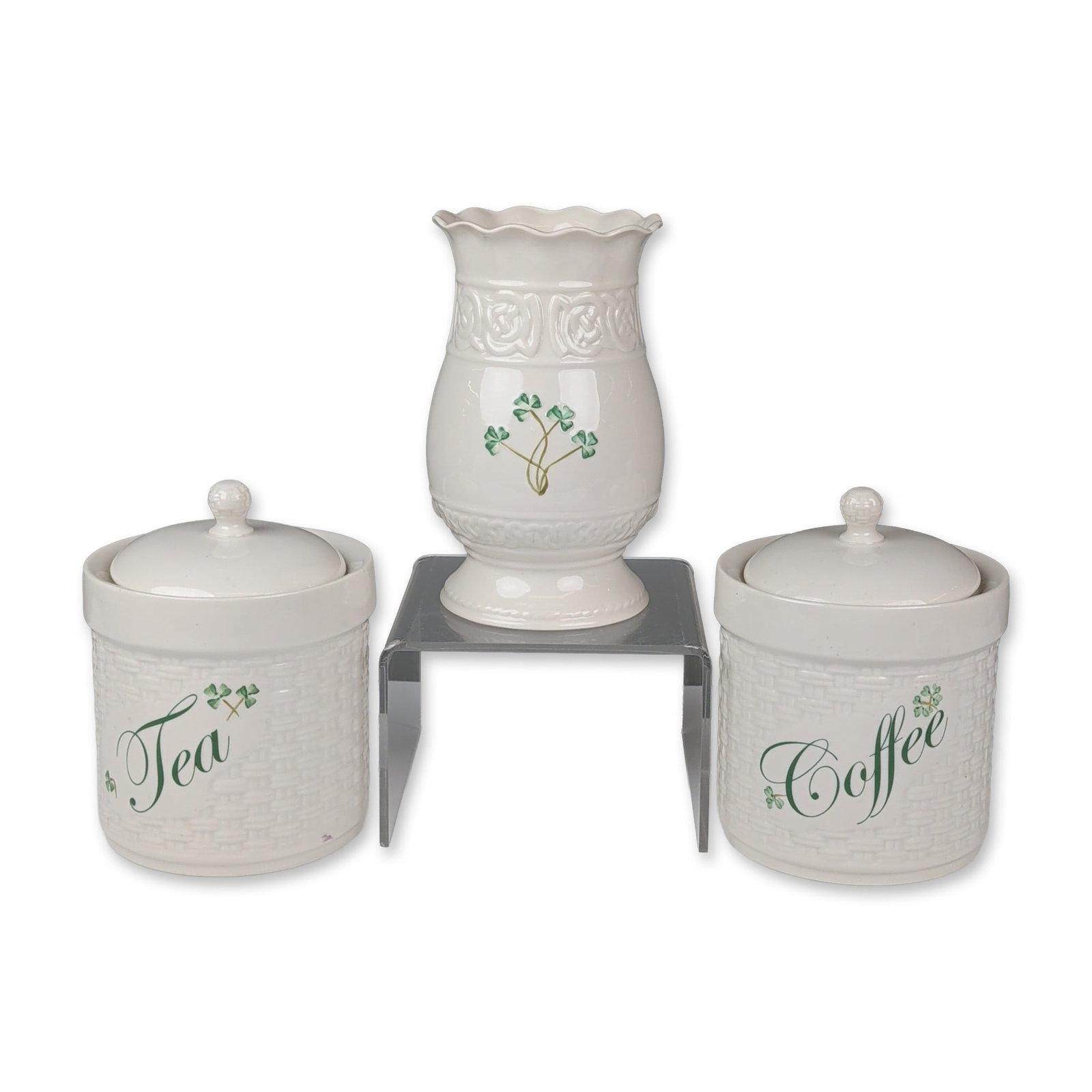 Three Belleek Irish Porcelain Shamrock Canisters and Vase: Three-piece ceramic group in glazed cream porcelain featuring hand-painted green shamrock decoration. The set includes two cylindrical canisters with molded basketweave bodies and lids, labeled Coffee