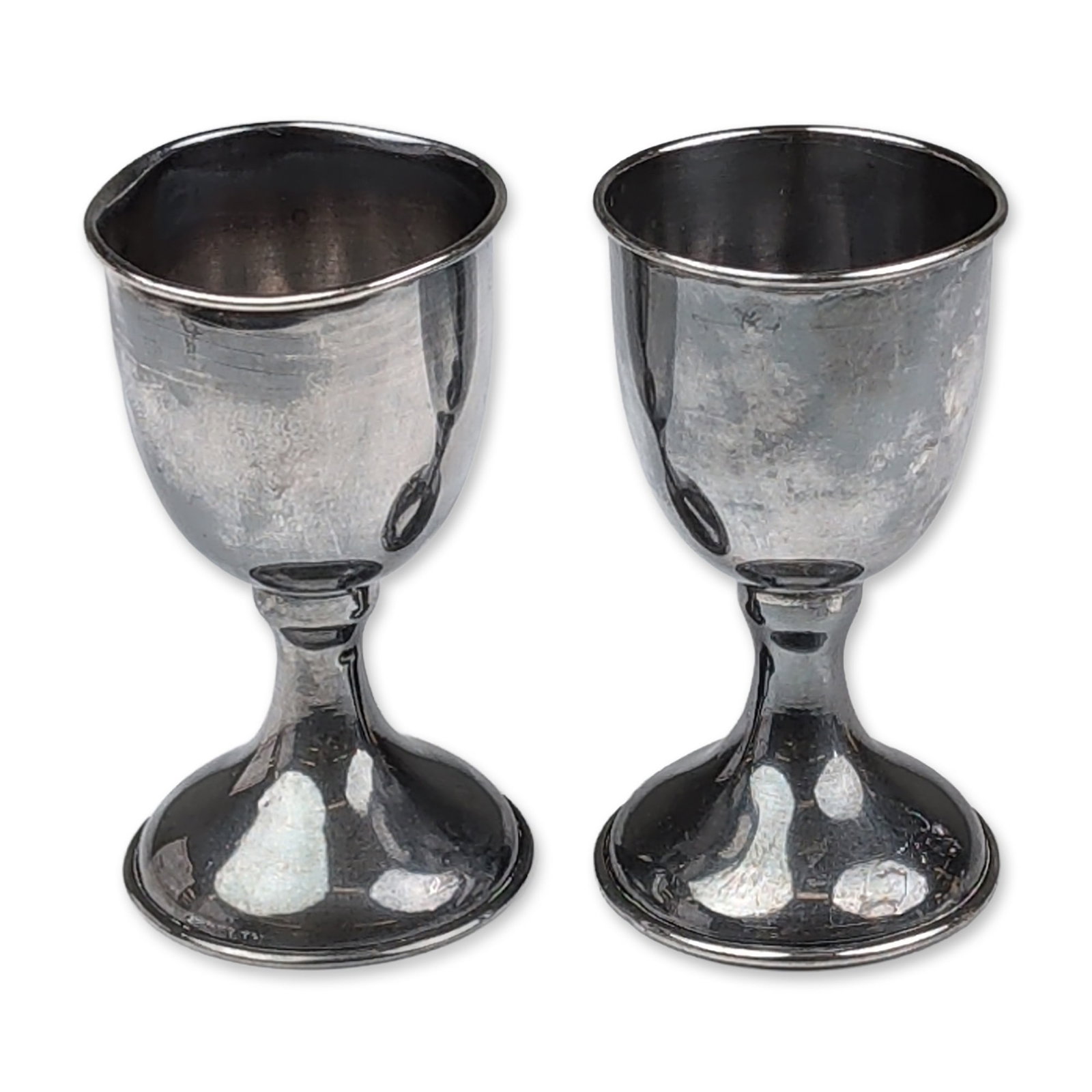 Pair of Sterling Silver Cordial Goblets: Pair of sterling silver cordial goblets featuring bell-shaped bowls with flared rims, tapered stems with central knops, and circular pedestal bases. An impressed mark reading STERLING is located on th
