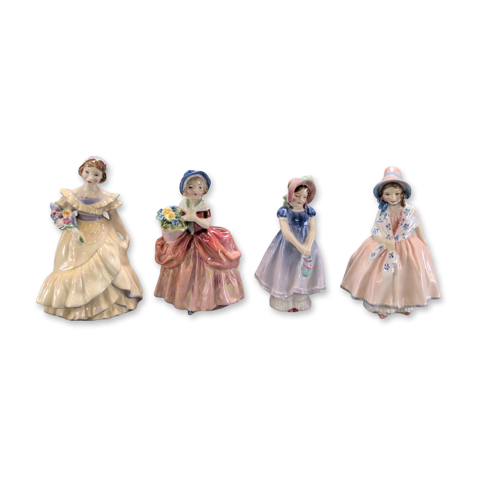4pc Royal Doulton Figurines: Royal Doulton. Four figurines in glazed porcelain, depicting young women in traditional attire. The group includes Lily in a pink and white dress, Ivy in a blue and lavender dress, Cissie in a red and