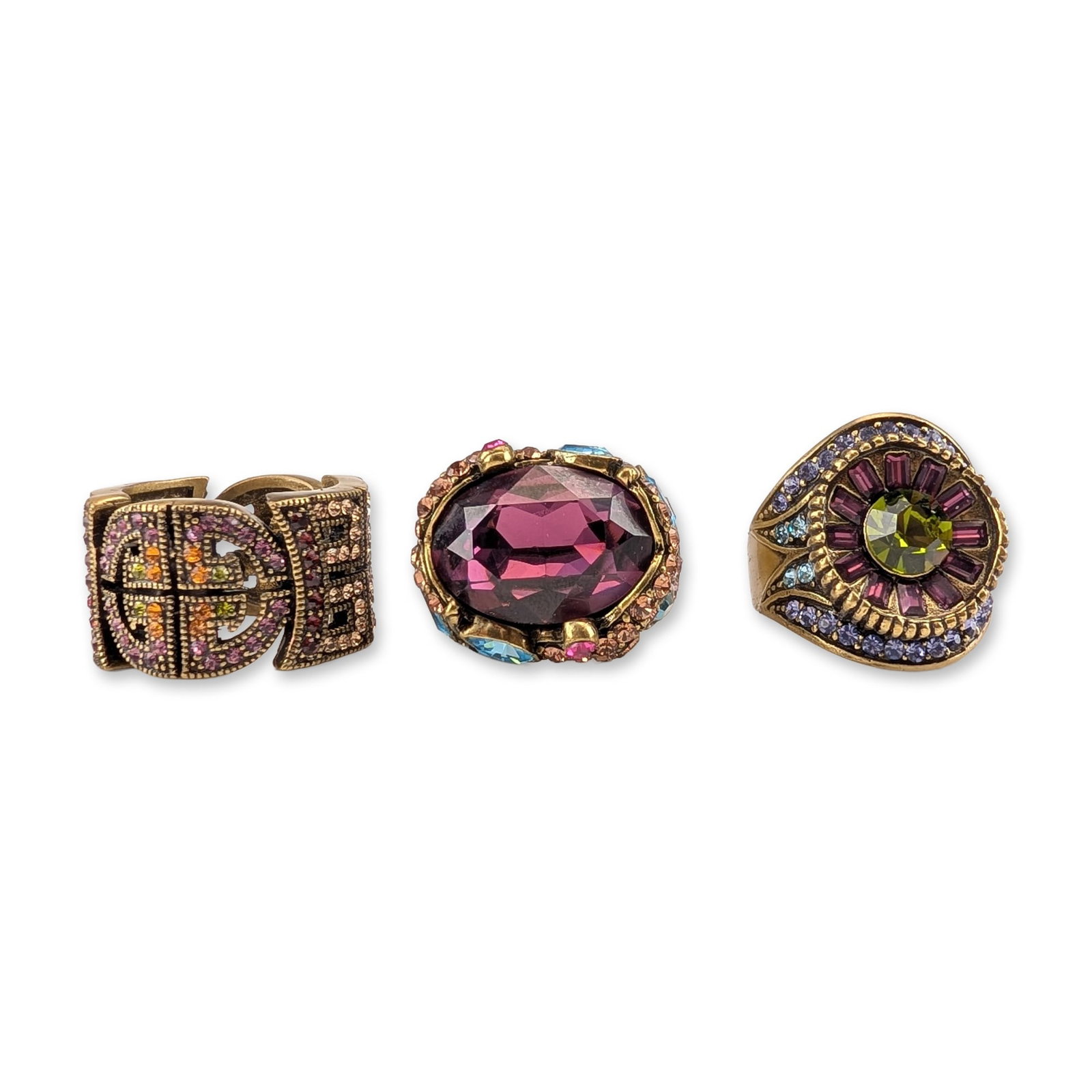 3pc Heidi Daus Bronzetone and Crystal Cocktail Rings: Three cocktail rings in antiqued bronzetone base metal set with faceted leaded glass crystals in various cuts. The group features a wide wrap-style band with geometric openwork motifs set with amethys