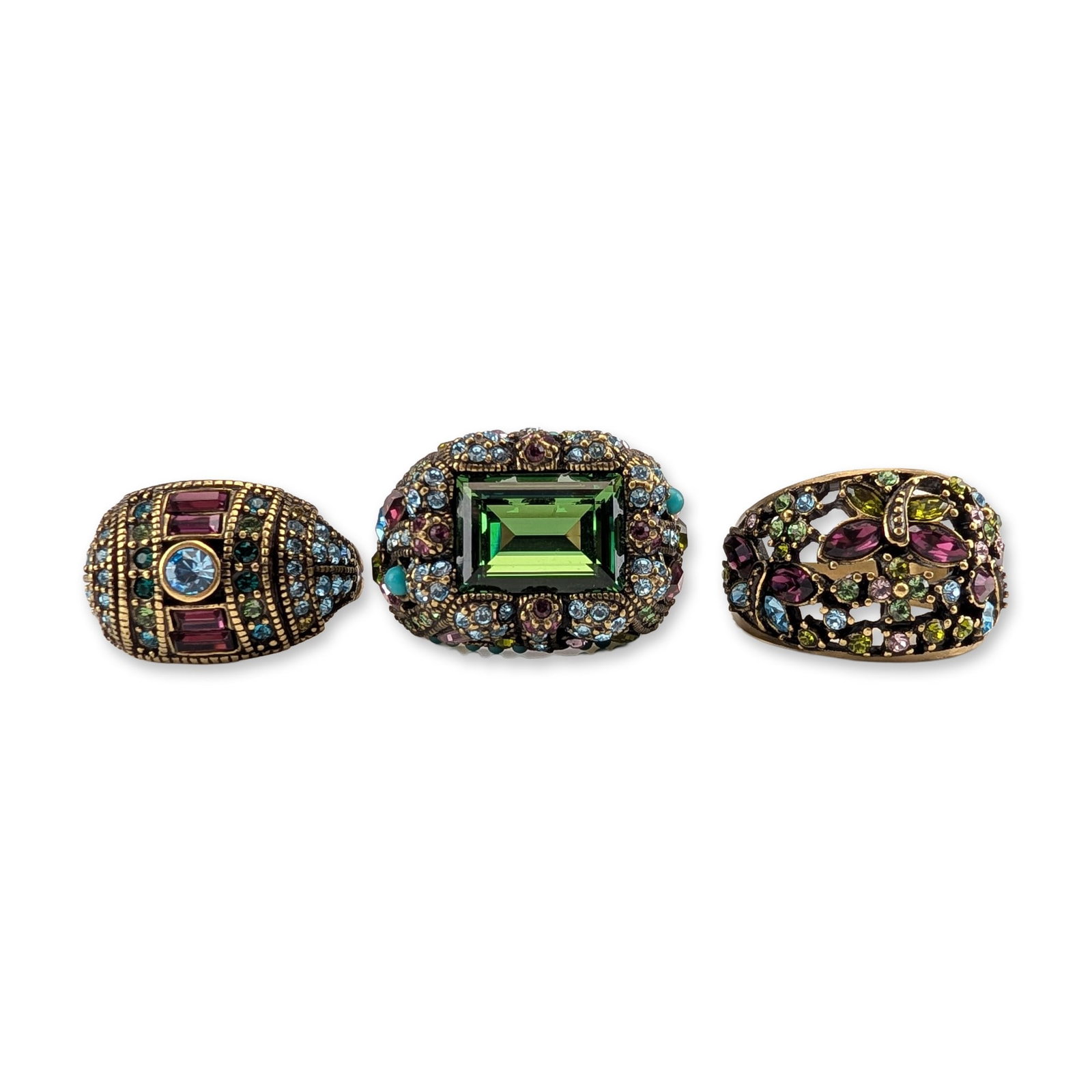 3pc Heidi Daus Designer Costume Cocktail Rings: Trio of cocktail rings in antiqued brass-tone metal, featuring multi-colored faceted crystals and cabochon accents. The collection includes a domed design with a central light blue crystal, burgundy c