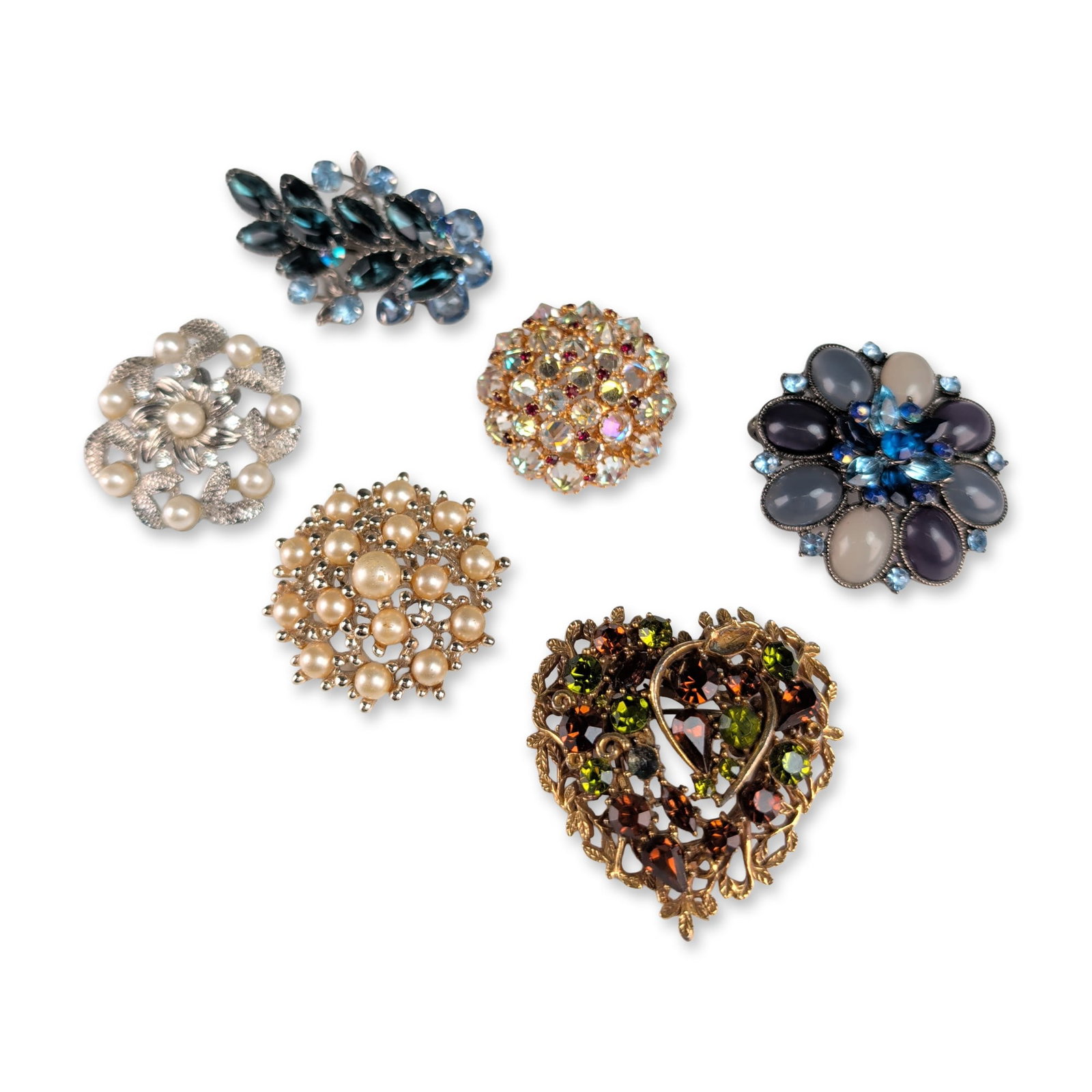 6pc Vintage Costume Brooches: Mid-20th century. Collection of six costume jewelry brooches in gold and silver-tone base metals, featuring various glass rhinestones, cabochons, and faux pearls. The lot includes a circular tiered go