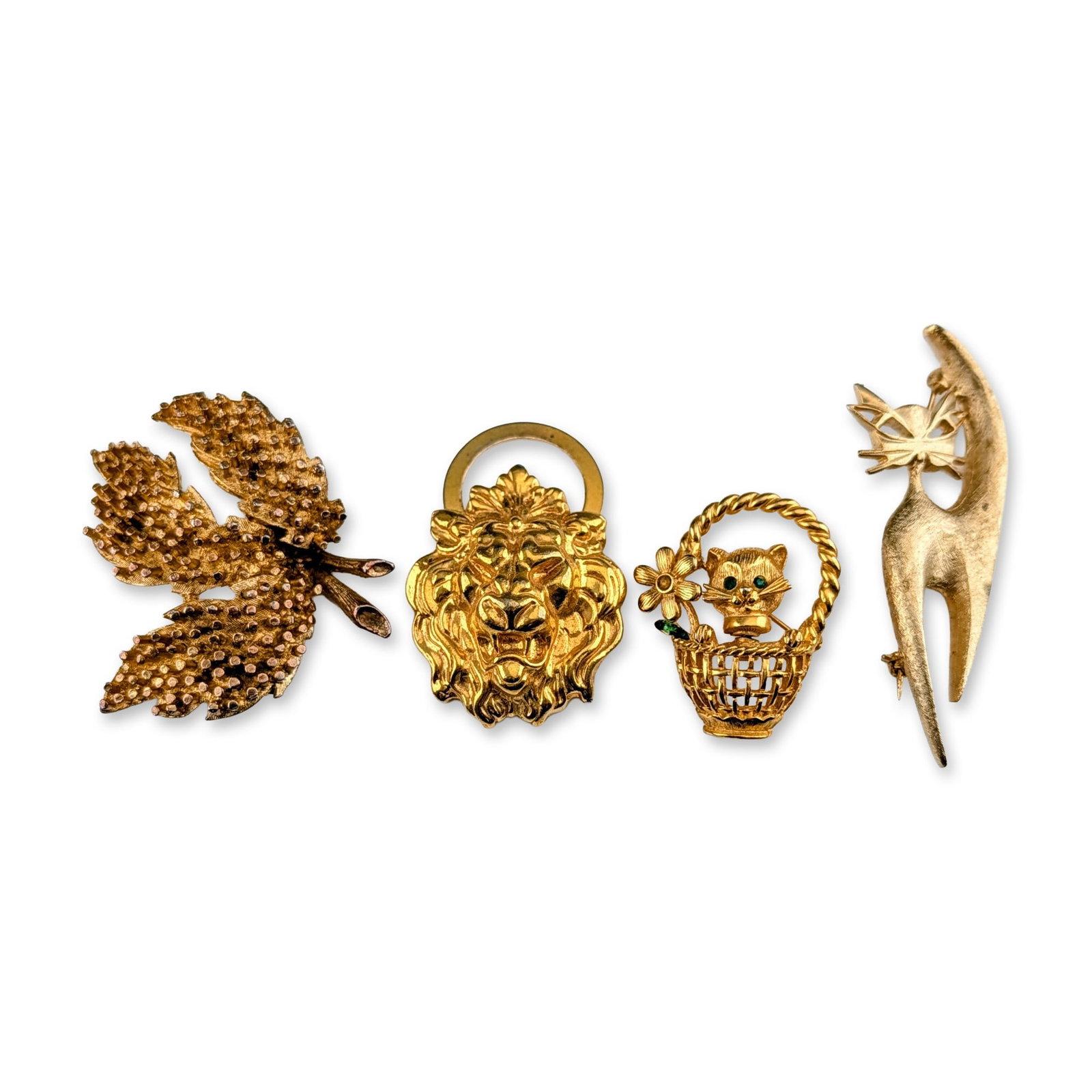 4pc Assortment of Vintage Gold Tone Animal and Botanical Jewelry: Group of four gold tone items, including three brooches and one scarf clip featuring animal and botanical motifs. The collection comprises a large textured multi-lobed leaf brooch, a roaring lion head