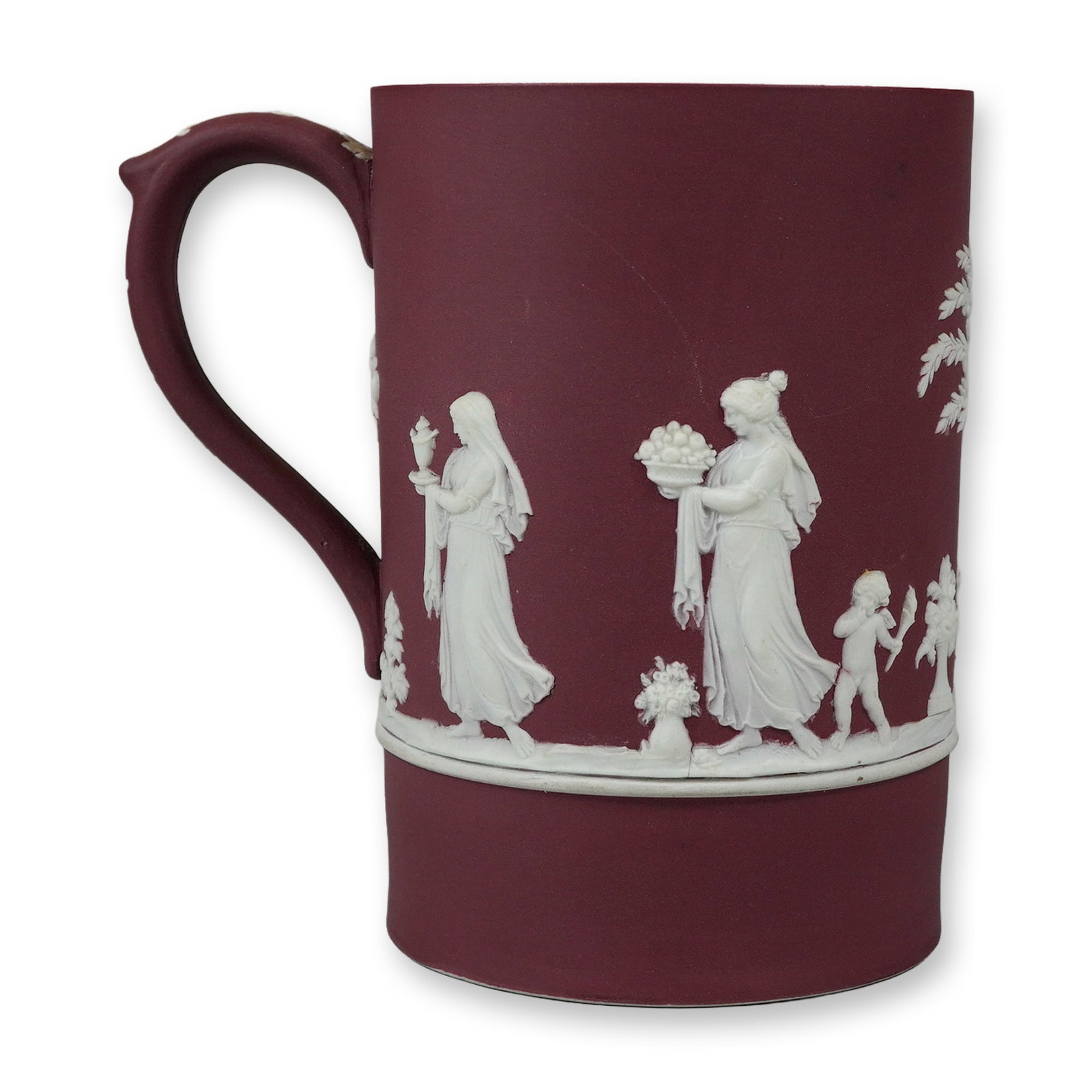Wedgwood Crimson Jasperware Dip Neoclassical Mug: The form is a straight-sided cylindrical mug with a shaped C-scroll handle featuring a thumb rest. The decoration is in the rare crimson colorway, characterized by white sprigged bas-relief neoclassic
