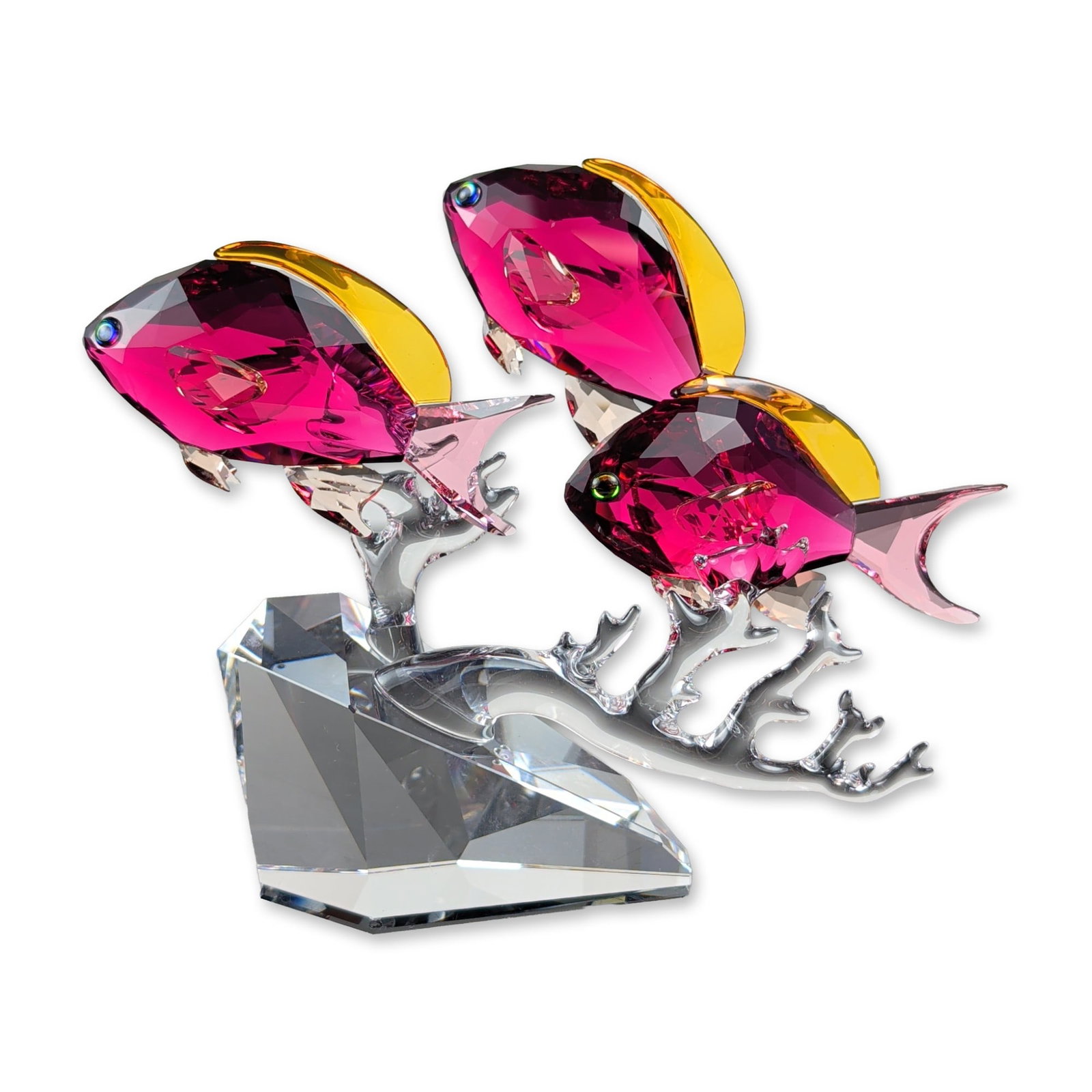 Swarovski Anthias Fish Trio Crystal Figurine: Swarovski Anthias Fish Trio figurine from the Crystal Paradise collection, featuring three fuchsia faceted crystal fish with yellow-toned dorsal fins and clear crystal tails. Set upon clear crystal co
