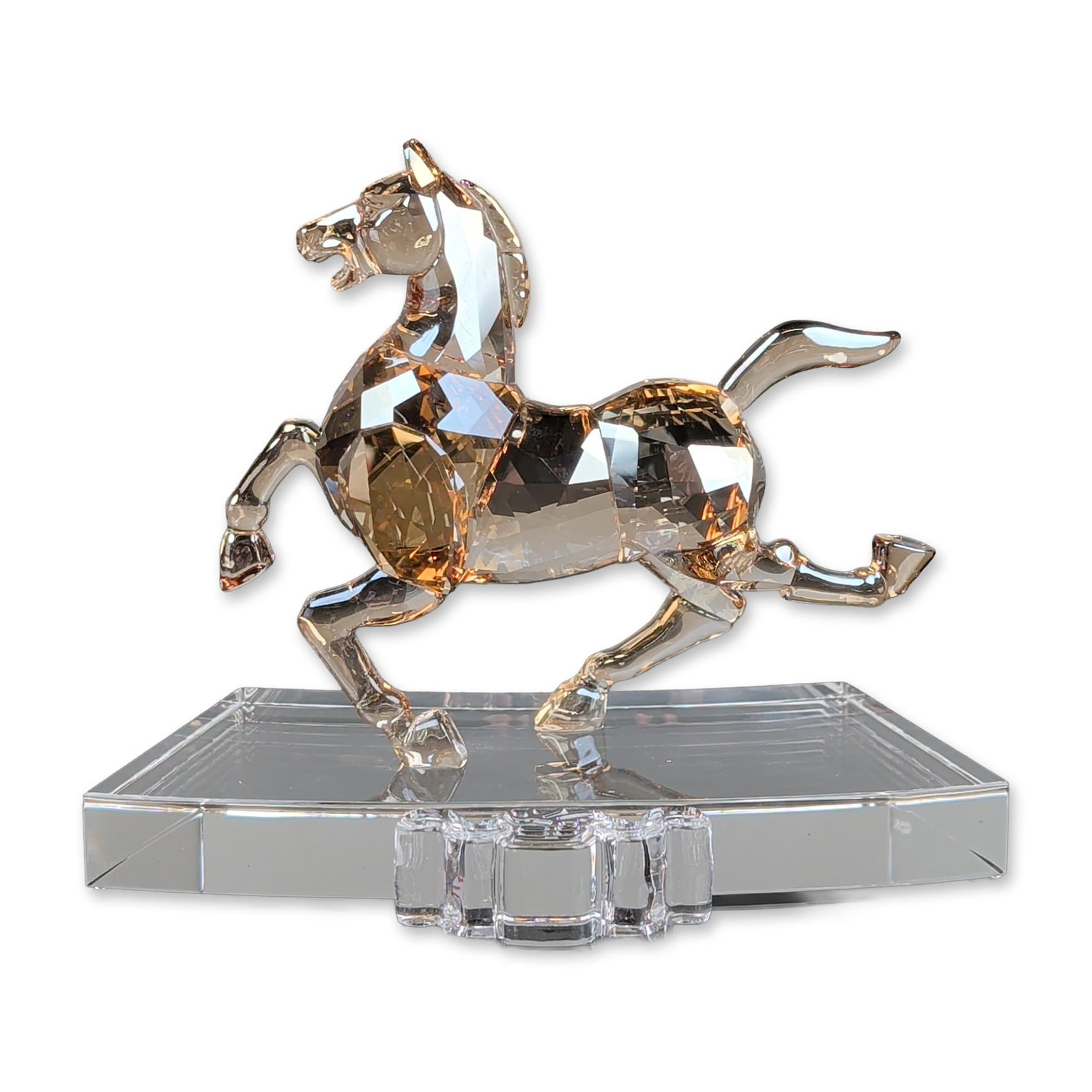 Swarovski Crystal Chinese Zodiac Figurine, Golden Crystal Horse: Swarovski Chinese Zodiac Horse figurine crafted in faceted Golden Shadow crystal with a clear crystal mane and tail. The horse is depicted in a galloping pose and is mounted to a curved clear crystal 
