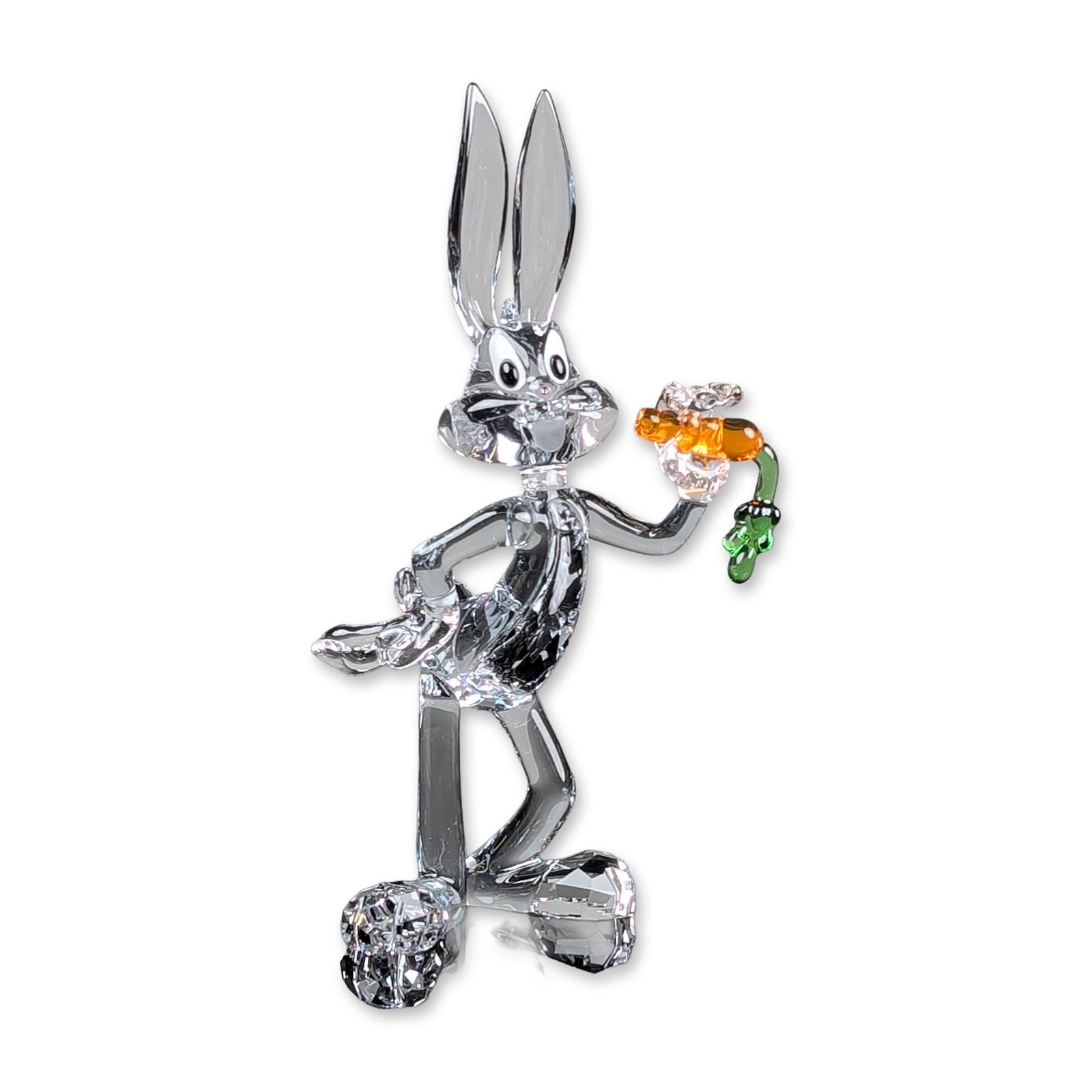 Swarovski Crystal Figurine, Warner Bros Looney Tunes Bugs Bunny: Swarovski Warner Bros Looney Tunes collection, Bugs Bunny figurine in clear faceted and smooth crystal, depicted in a reclining pose holding a carrot crafted from orange and green crystal. Features de