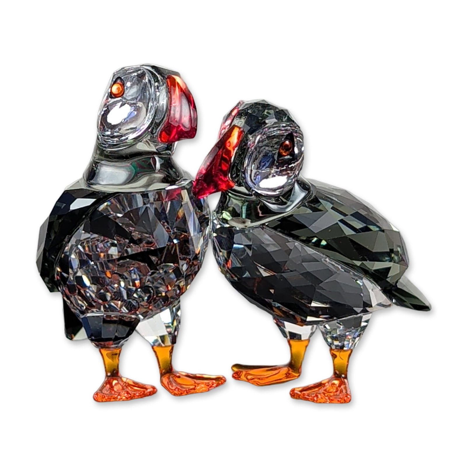 Swarovski Crystal Atlantic Puffins Pair Figurine: Swarovski faceted lead crystal figurine depicting Atlantic puffins pair, model 5472475. Each bird is constructed with a dark grey faceted crystal body and head, a clear faceted breast section, and ora