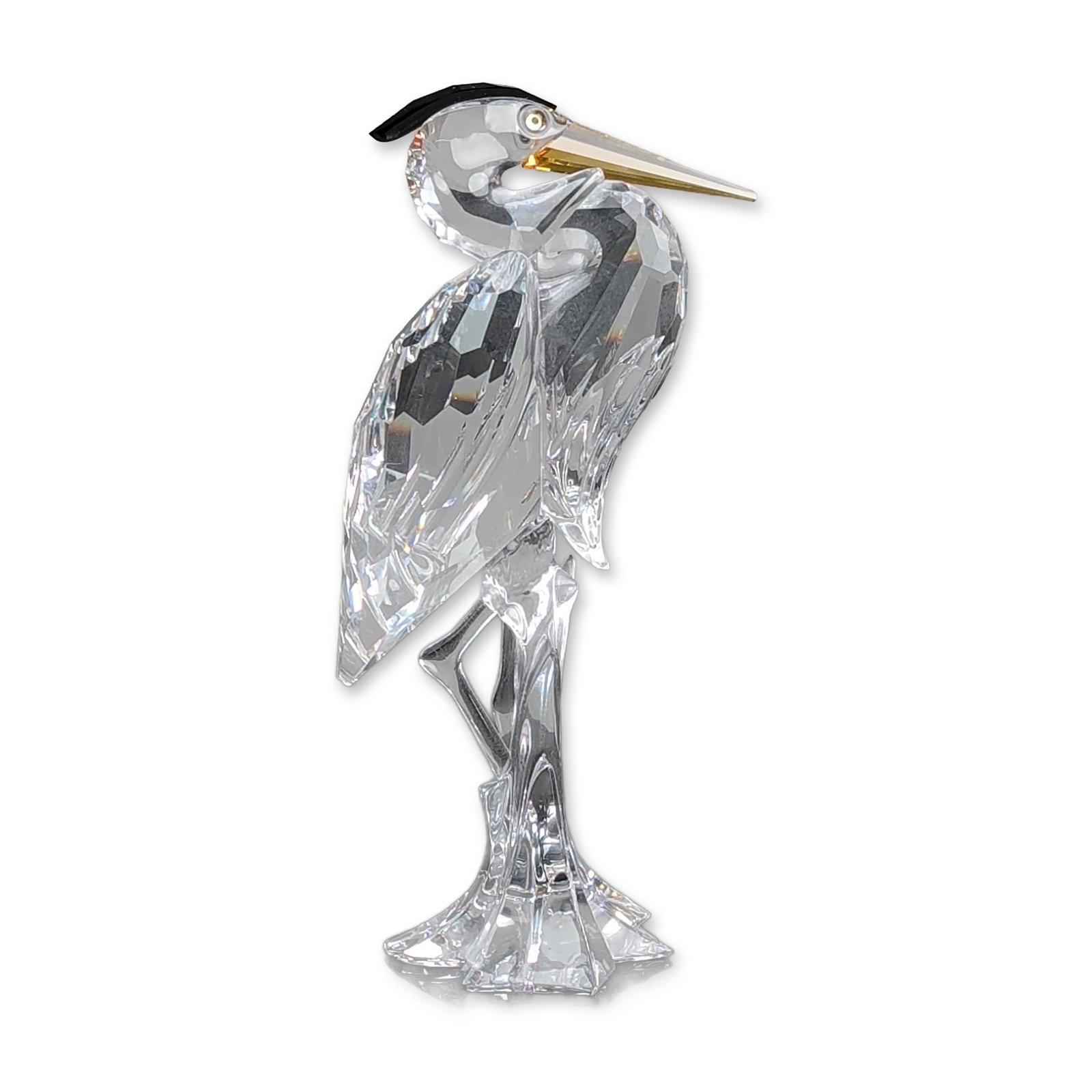 Swarovski Silver Crystal Heron Figurine 221627: Silver Heron figurine crafted from faceted clear lead crystal, the figurine features a tapered yellow crystal beak and a small black crystal feather crest. The bird is depicted in a standing pose atop