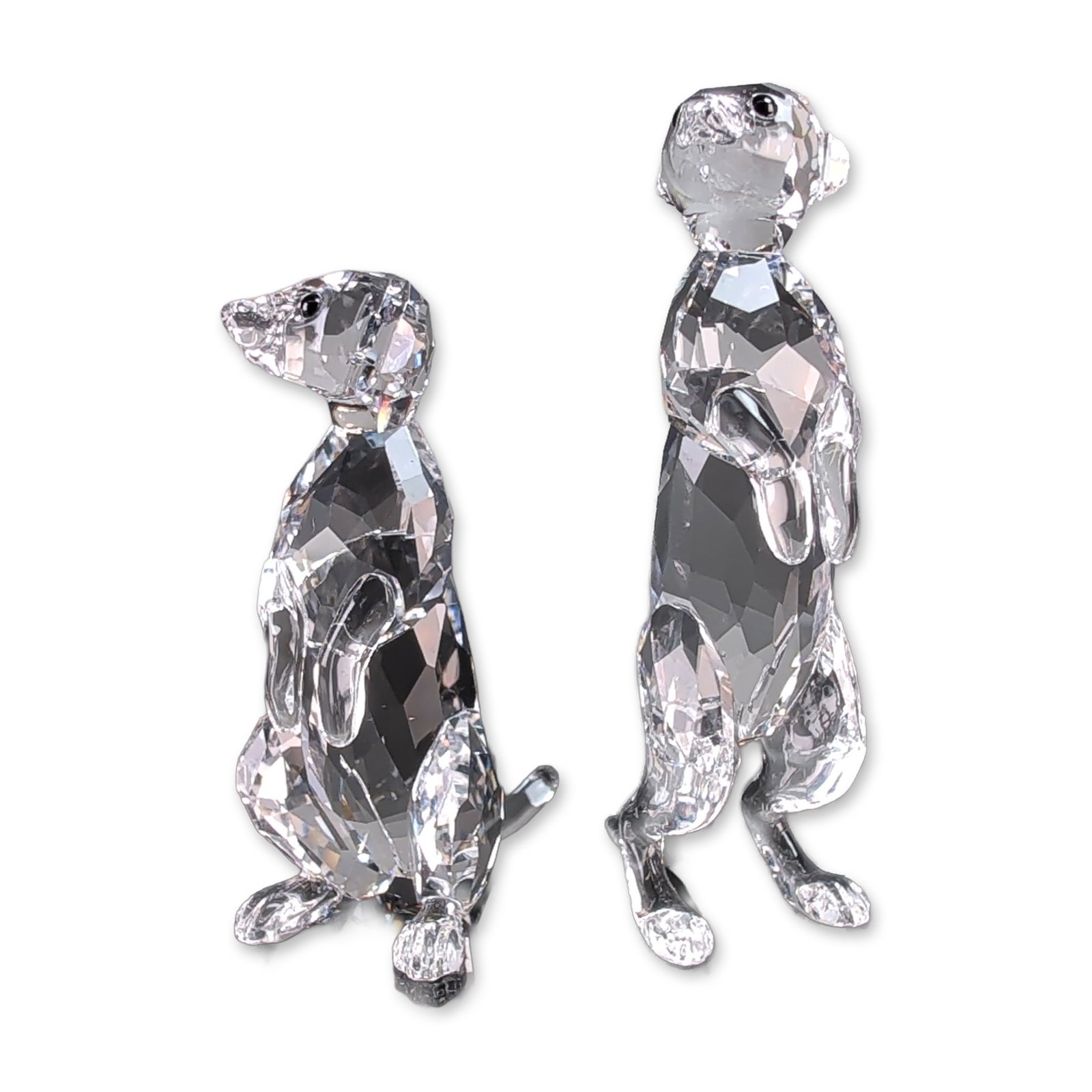 Pair of Swarovski Crystal Meerkats Figurines: Swarovski pair of meerkats figurines in faceted clear crystal. Each figure features a faceted body and head in a standing pose, accented with small round black crystal eyes and a smooth curved tail. S