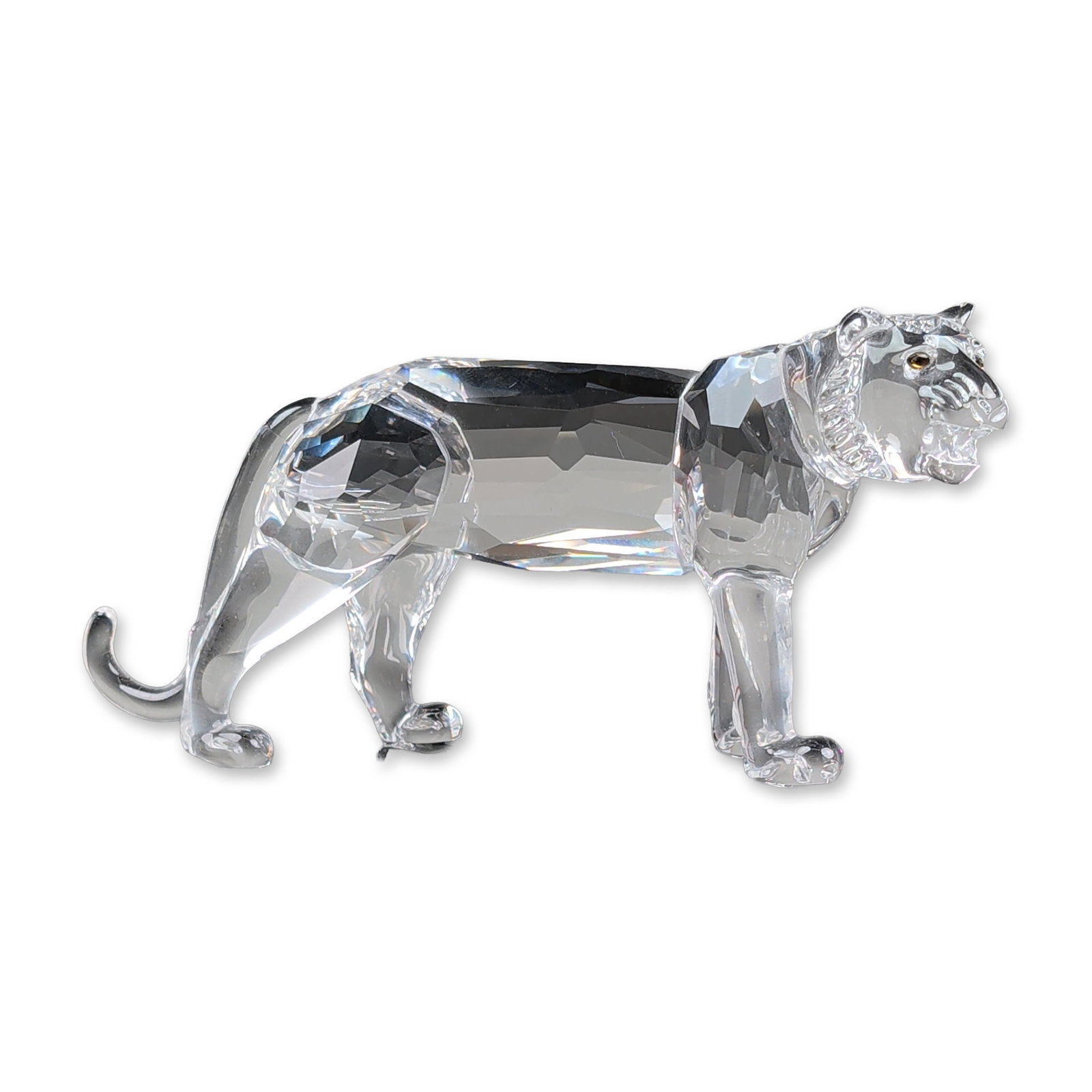 Swarovski Silver Crystal Tiger Figurine: Swarovski Silver Crystal tiger figurine in faceted and molded clear lead crystal. The standing figure features a molded head with mane and facial details, set with amber crystal eyes. The body and leg