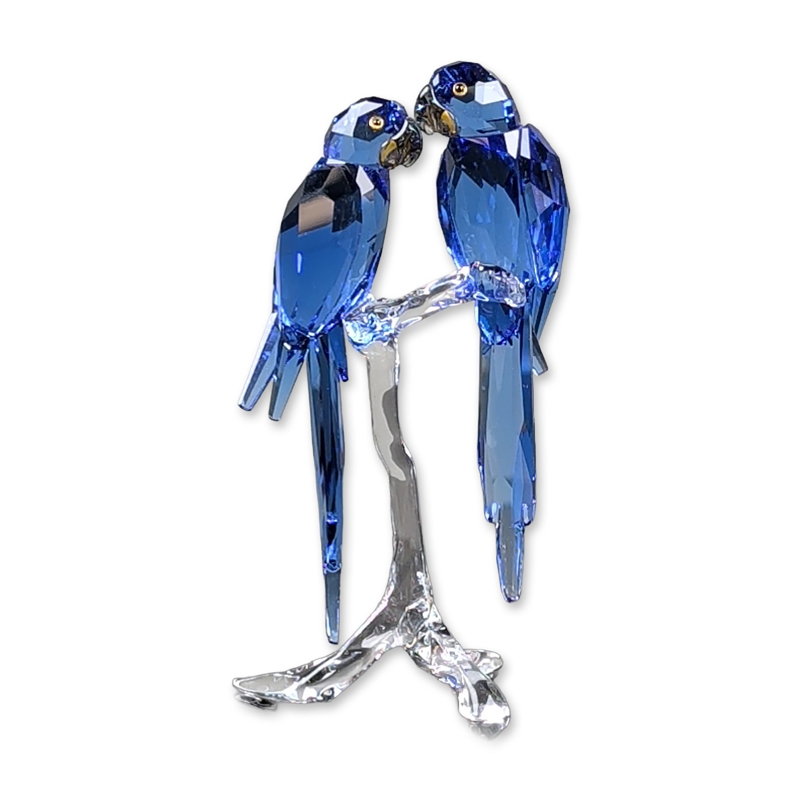 Swarovski SCS Hyacinth Macaws Crystal Figurine: Swarovski Crystal Society (SCS) figurine titled Hyacinth Macaws. The piece features two parrots in faceted deep blue crystal with yellow and black eyes, perched on a clear faceted crystal branch. A la