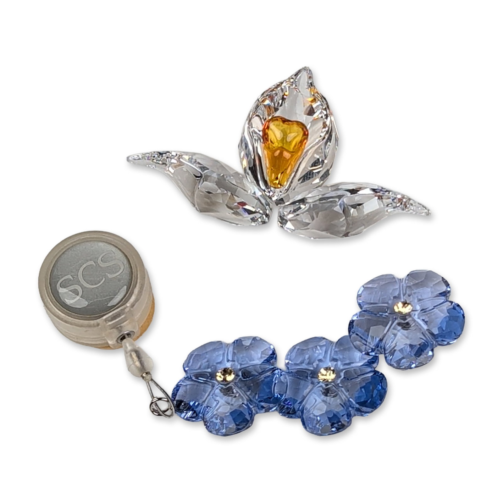 Two Swarovski SCS Crystal Flower Figurine and Ornament: Two faceted crystal floral items including an African Orchid designed with clear blossom, three petals and an amber center; also included is an Arctic Flower with a string of three blue forget-me-not 