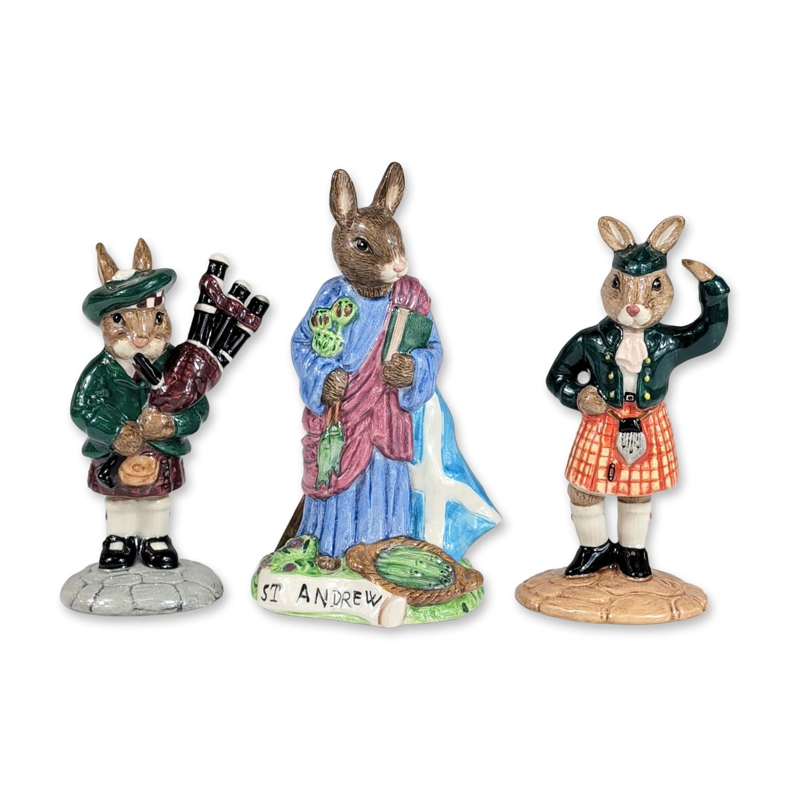Three Royal Doulton Scottish Ceramic Bunnykins Figurines: Royal Doulton. Three Bunnykins figurines in glazed ceramic depicting traditional Scottish themes. The group consists of Scotsman Bunnykins (DB 180), St. Andrew Bunnykins (DB 399), and Piper Bunnykins 