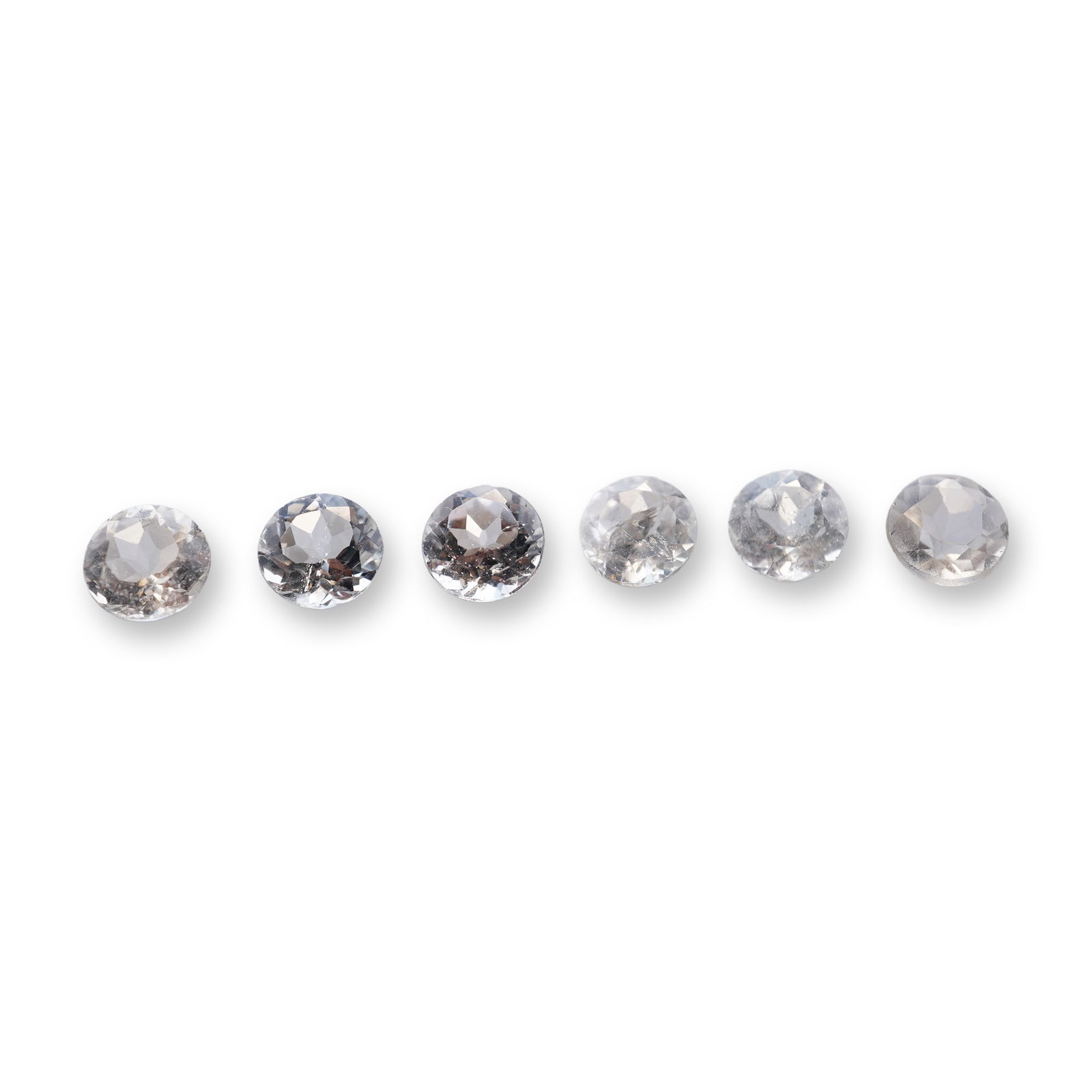 Group of Round Faceted Colorless Aquamarine Gemstones: Group of colorless aquamarine gemstones, round faceted featuring multi-faceted crowns and pointed pavilions. The stones exhibit internal inclusions including veils, clouds, and small crystals. One exa