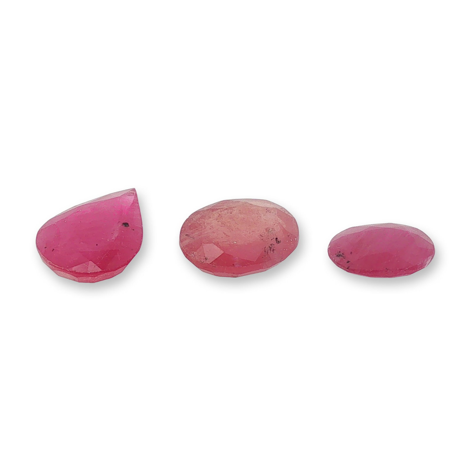 Three Loose Purplish Red Mixed Shape Gemstones: Trio of loose faceted gemstones. The set includes one pear cut and two oval cut gemstones of graduated sizes, all showcasing a distinct purplish-red hue. Each stone displays unique natural characteris