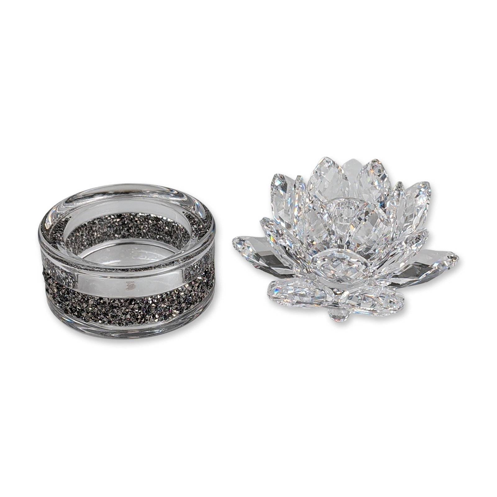 Two Swarovski Crystal Waterlily Rosaline Candle and Tea Light Holder: Decorative grouping in faceted clear crystal, featuring an open waterlily flower figurine and a Shimmer tea light holder with a band of dark crystal chaton accents. Both pieces bear the etched Swarovs