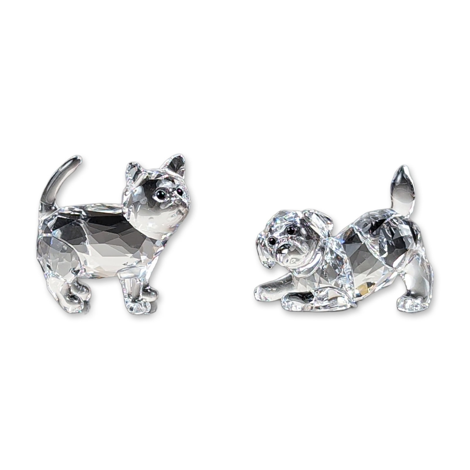 2pc Swarovski Crystal Kitten and Puppy Figurines: Swarovski. A pair of faceted clear lead crystal animal figurines, including a standing kitten and a playful puppy. Each piece is constructed from faceted clear crystal with black bead accents for the 